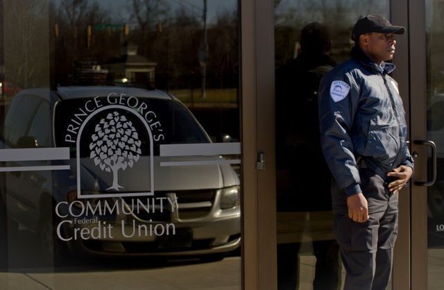 A security guard standing in front of a community credit union