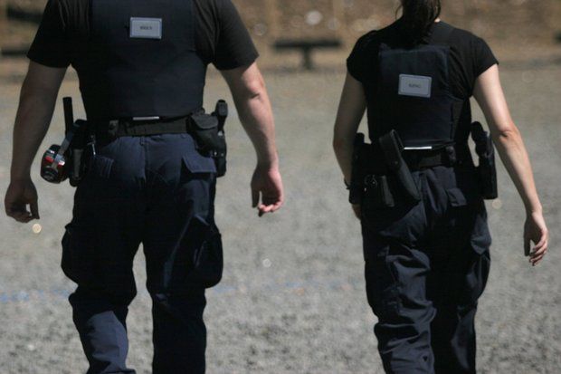 A man and a woman in police uniforms are walking away from the camera