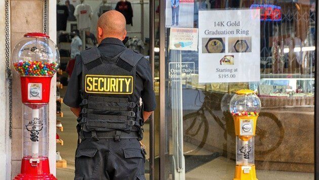 A security guard is standing in front of a gumball machine in a store.