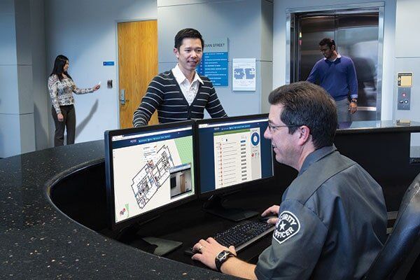 A man is sitting at a desk in front of two computer monitors.