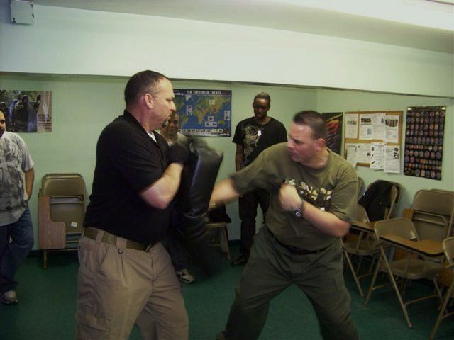 Two men are fighting in a room with a map of the world on the wall