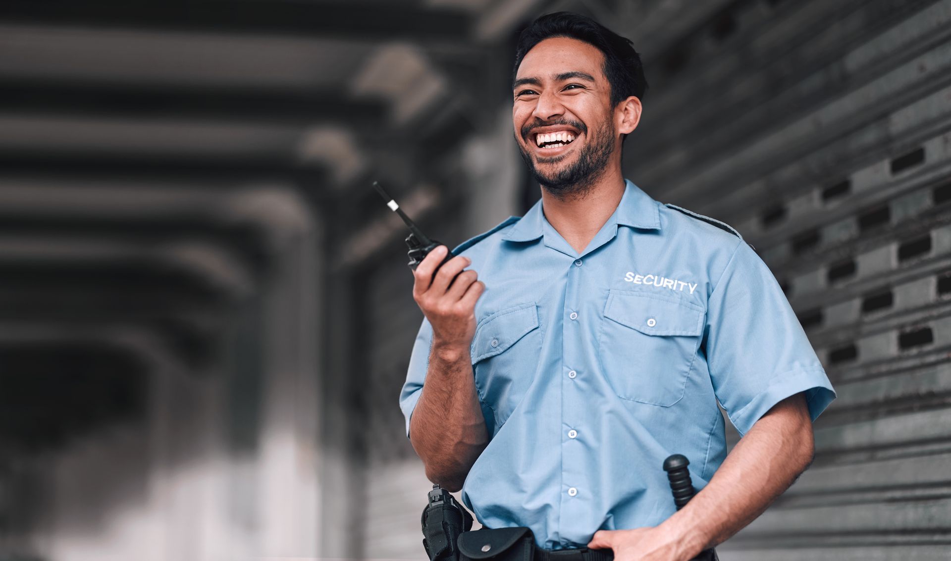 Security guard in blue uniform holding a walkie-talkie in an industrial setting.