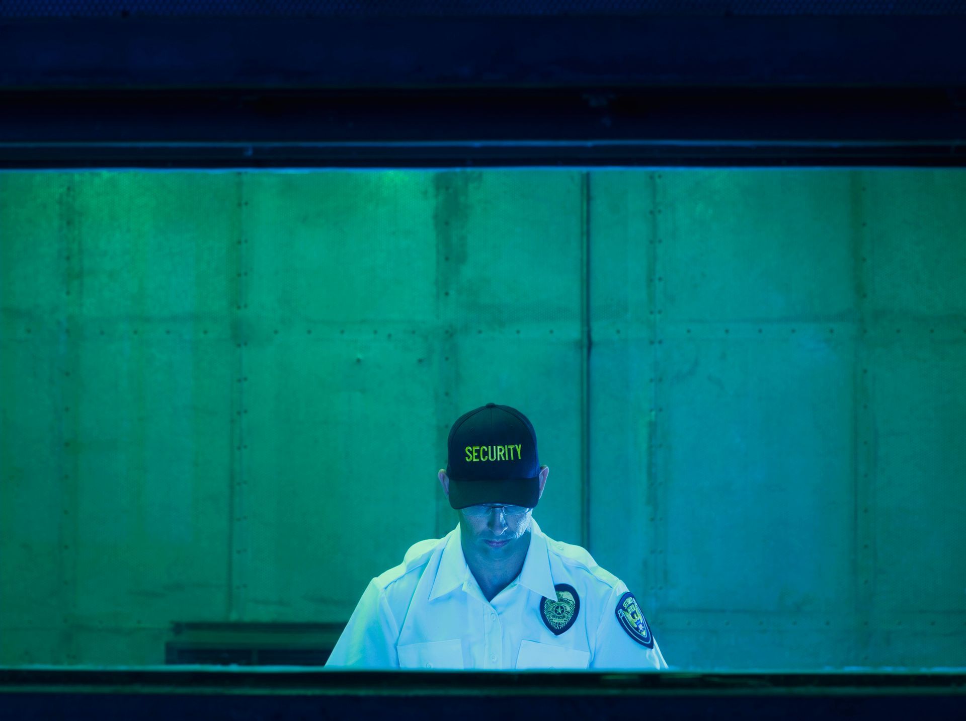 Security guard in uniform standing behind a glass window.