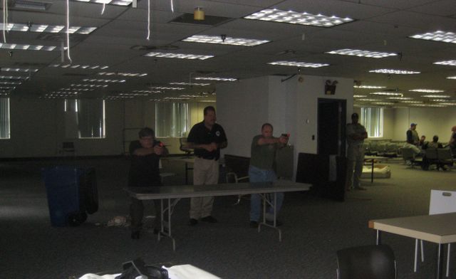 A group of people standing around tables in an empty room