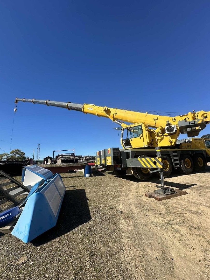 Yellow crane on wheels with extended arm, outdoors, on a sunny day — Crane Rentals in Taree, NSW
