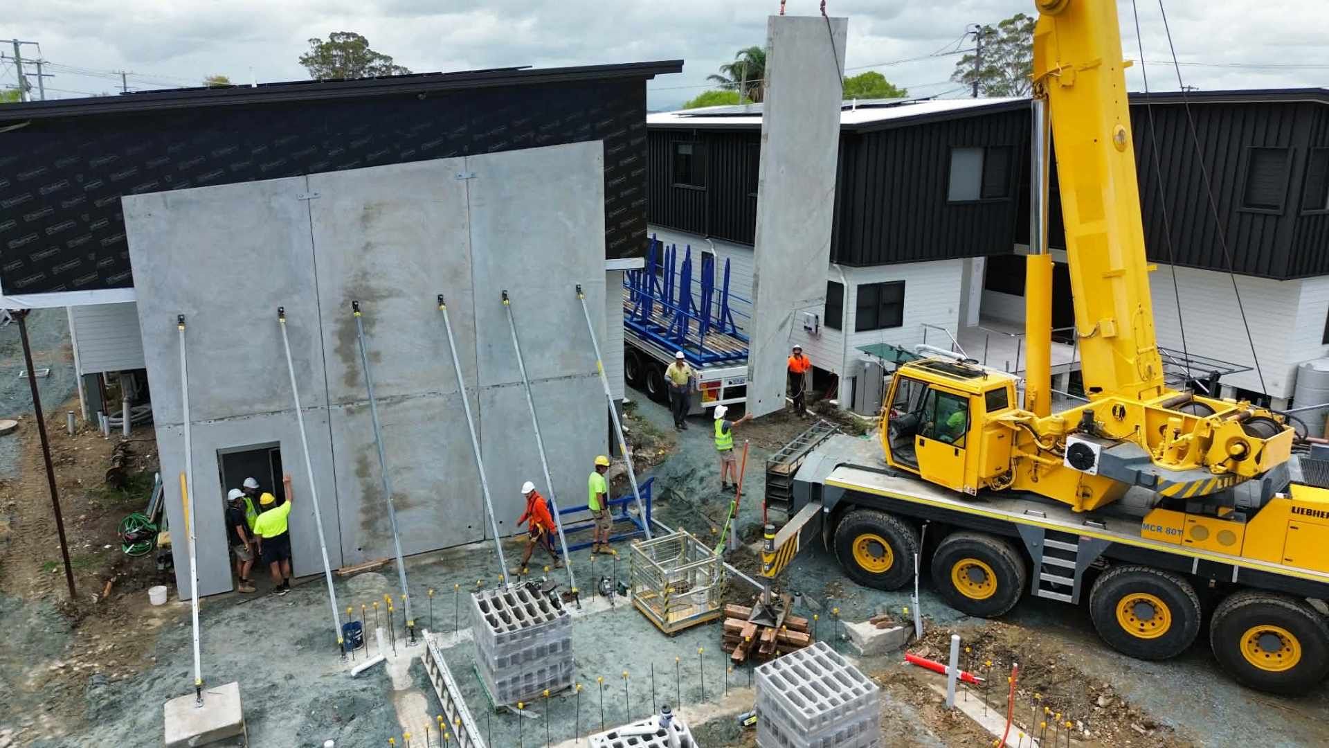 Construction Site With Crane Lifting Concrete Wall — Crane Rentals in Taree, NSW