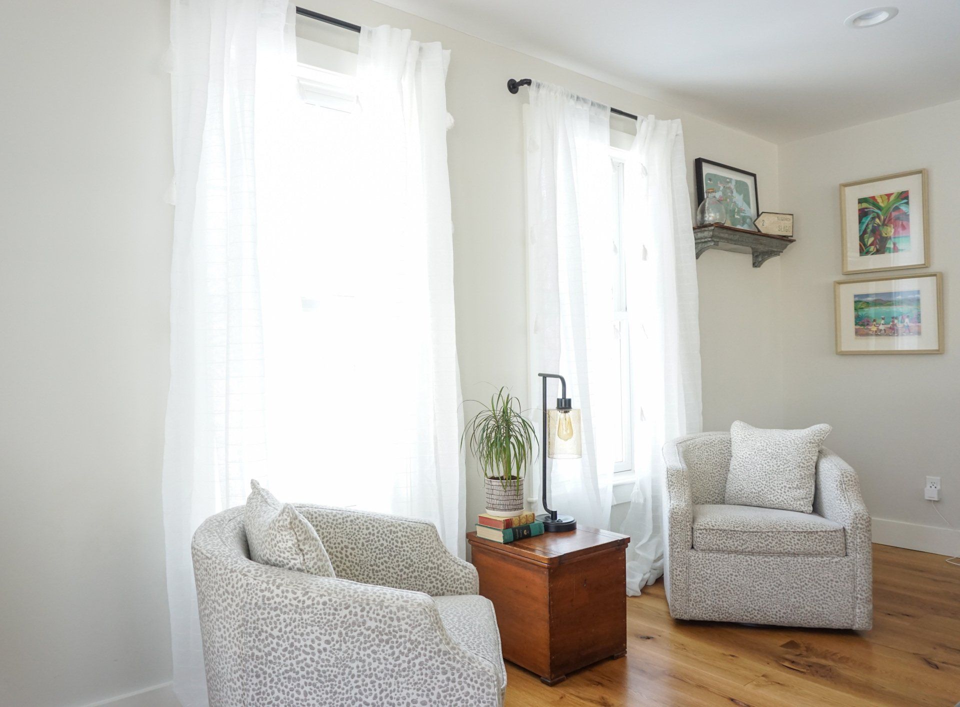 A living room with two chairs , a table , and a lamp.