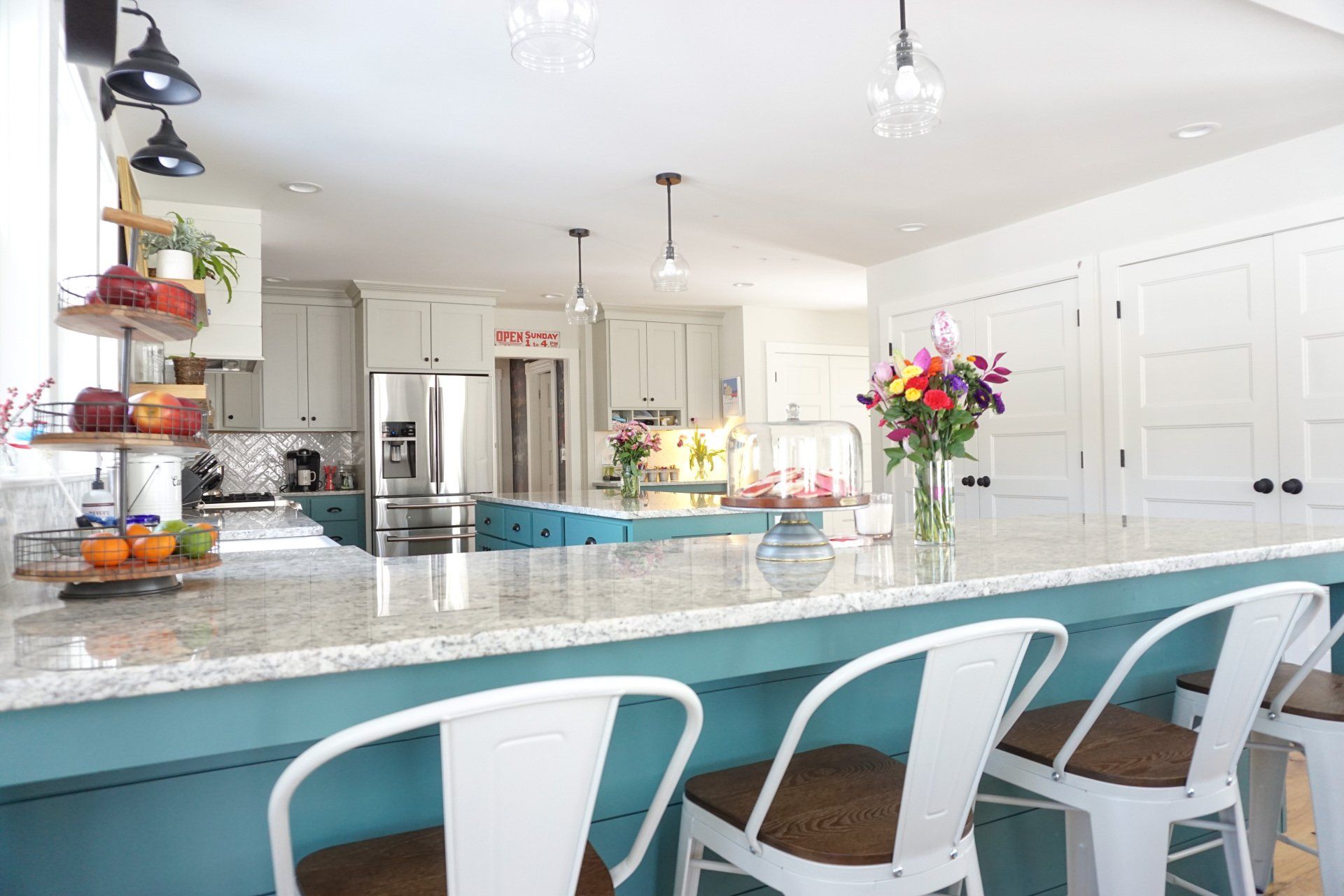 a kitchen with blue cabinets and white stools has a sign above the refrigerator that says
