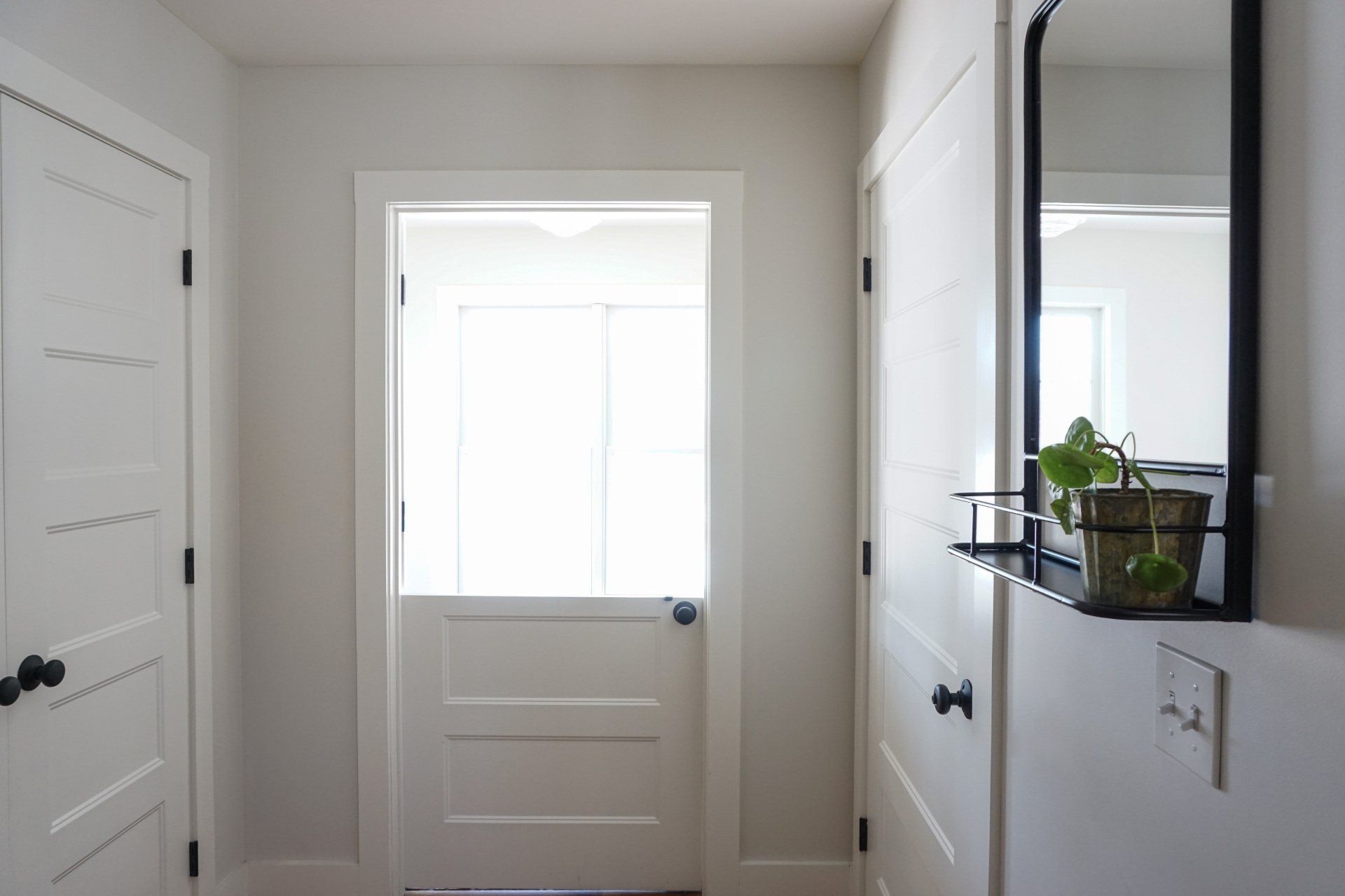 A hallway with white doors and a mirror on the wall