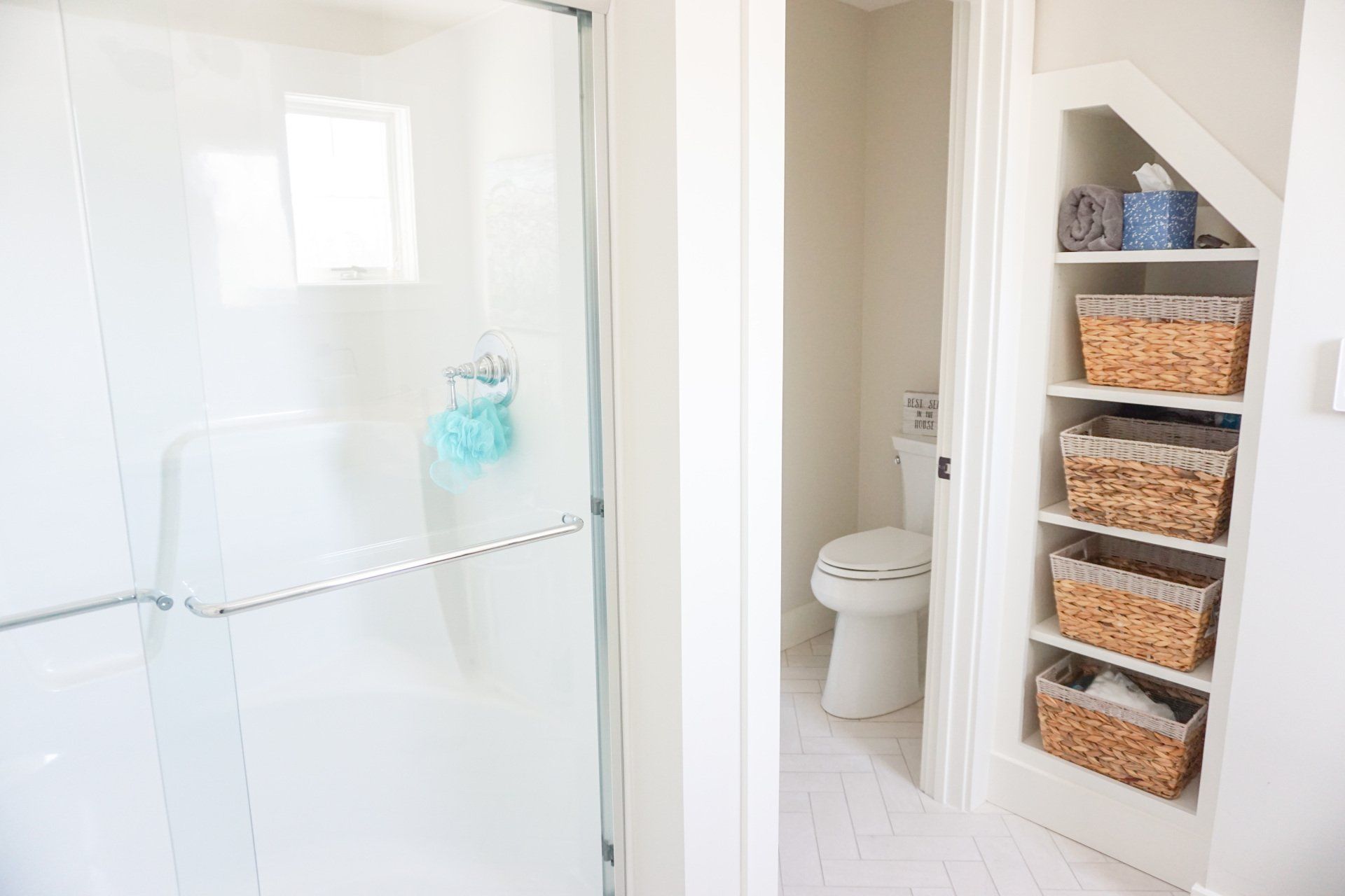 new bathroom renovations featuring walk in shower, shelf with wicker baskets for storage and a toilet with a door