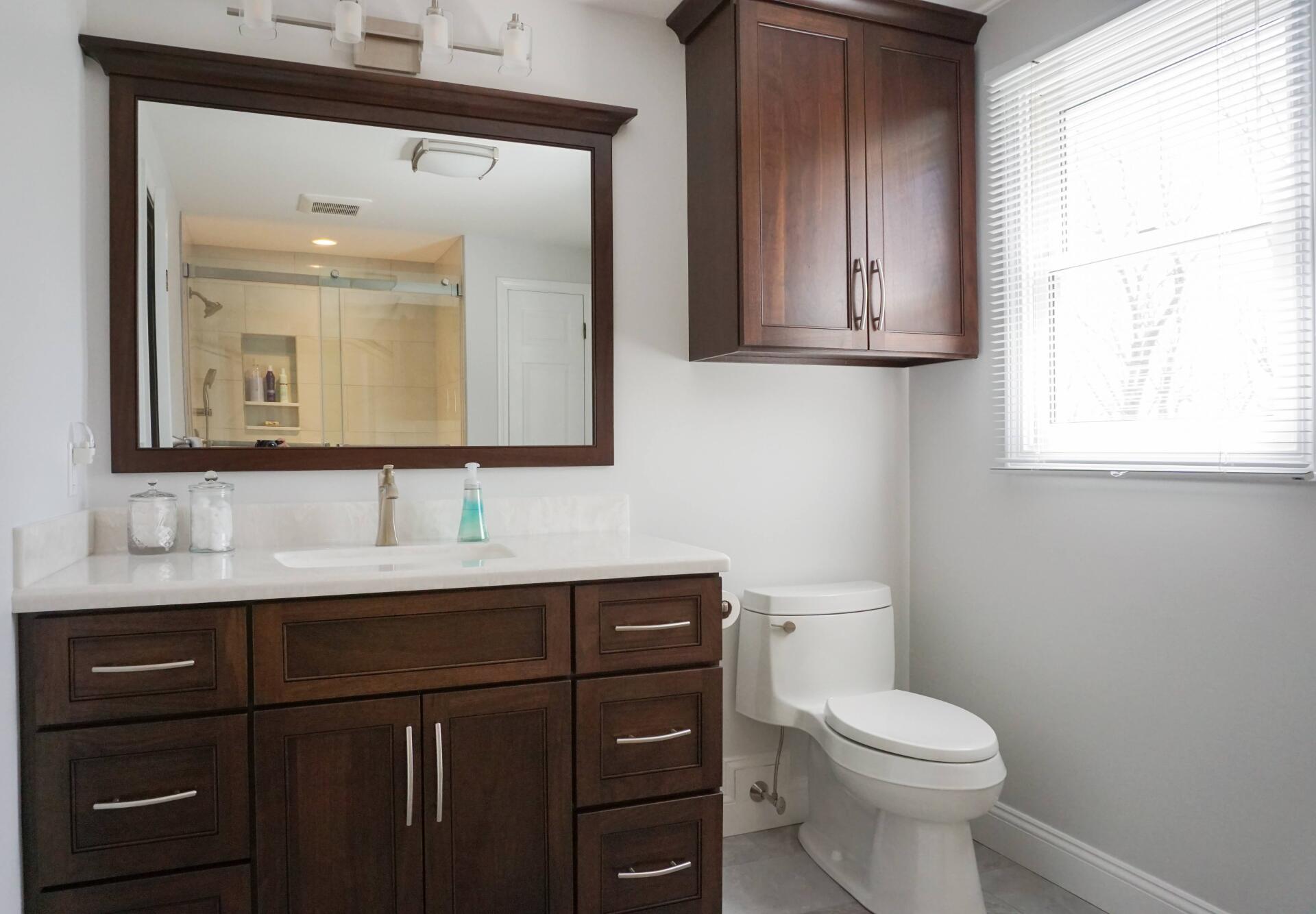 traditional bathroom remodel with white countertop, dark wood stain vanity, cabinets and mirror