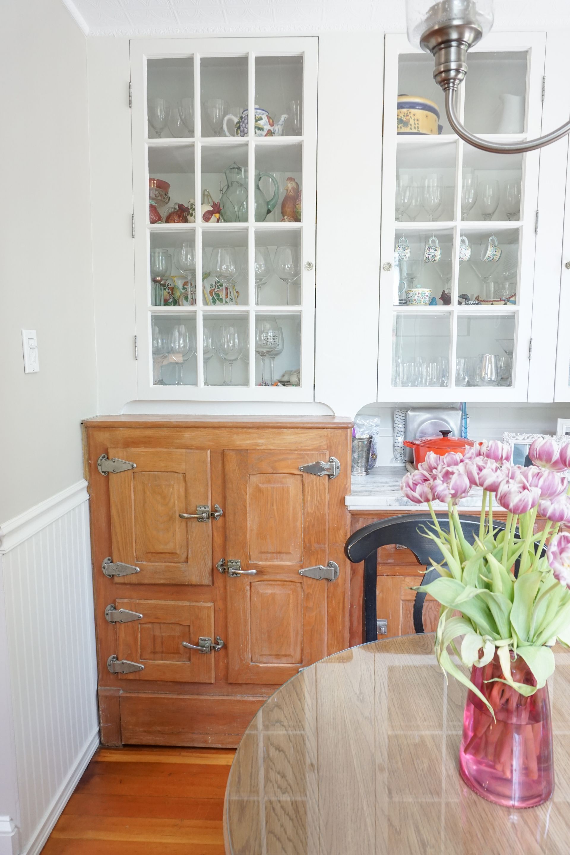 a kitchen with a glass cabinet and a vase of flowers on the table