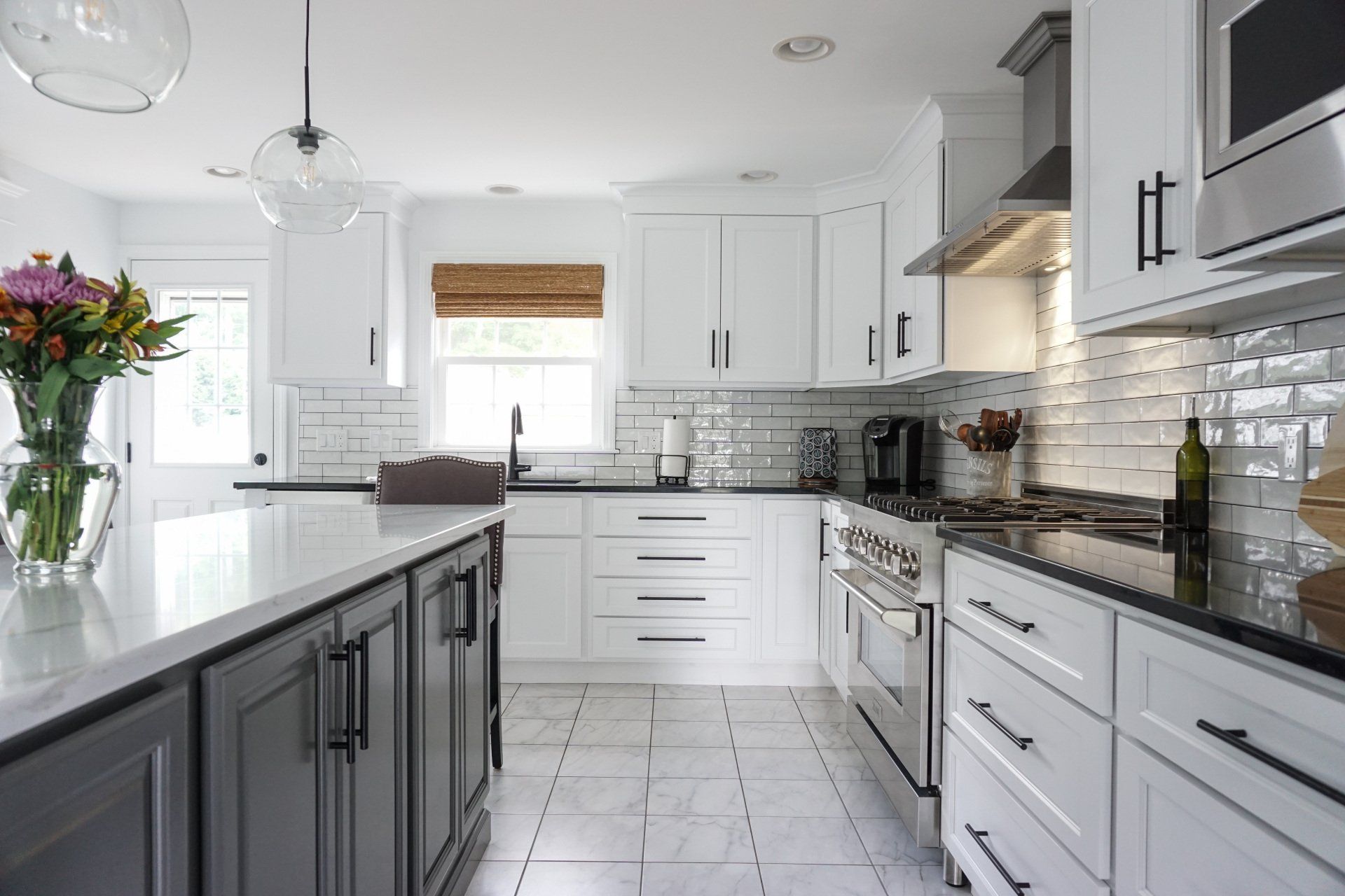 a kitchen with white cabinets and black handles