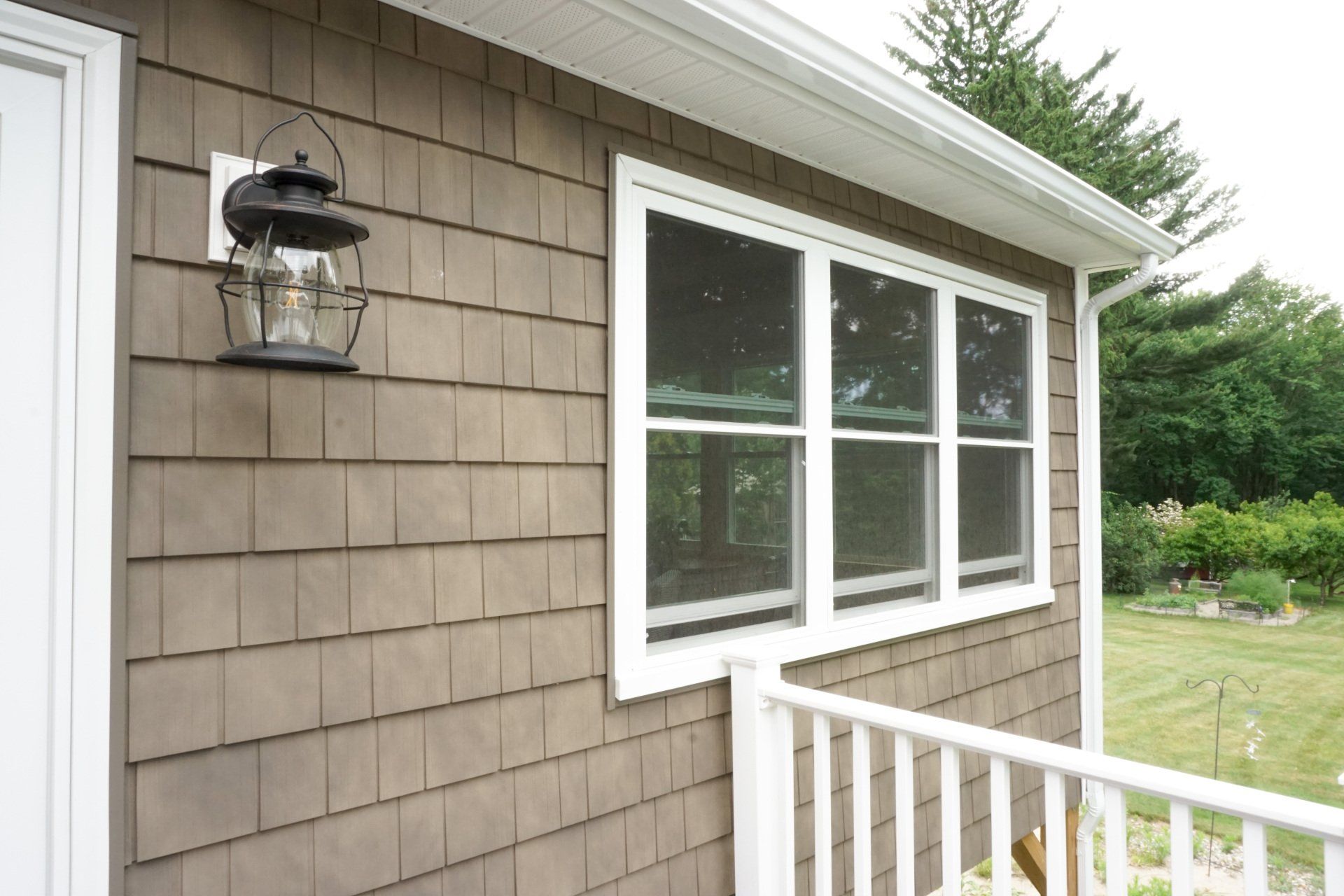 A lantern hangs on the side of a house next to a window
