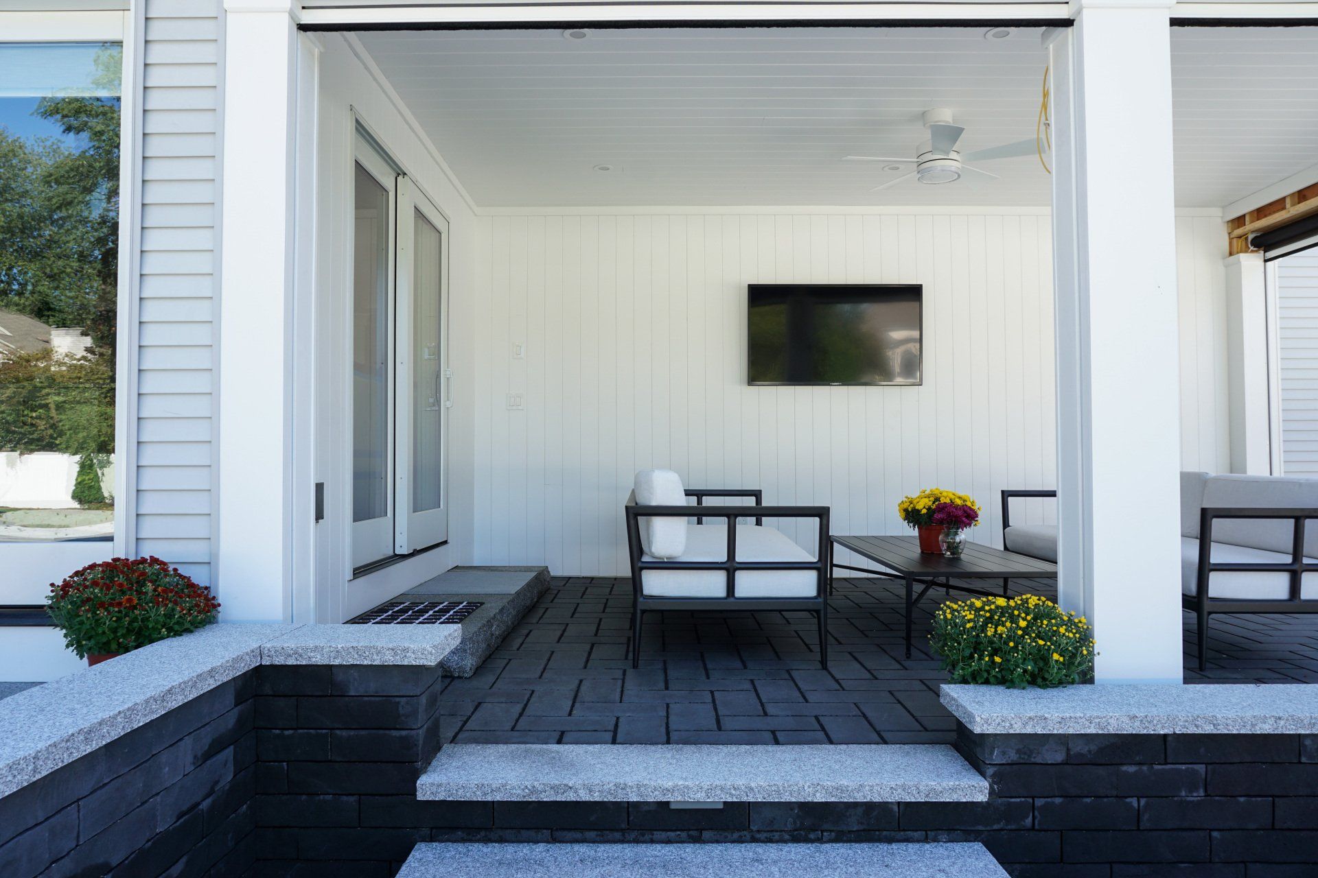 A patio with furniture and a flat screen tv on the wall.