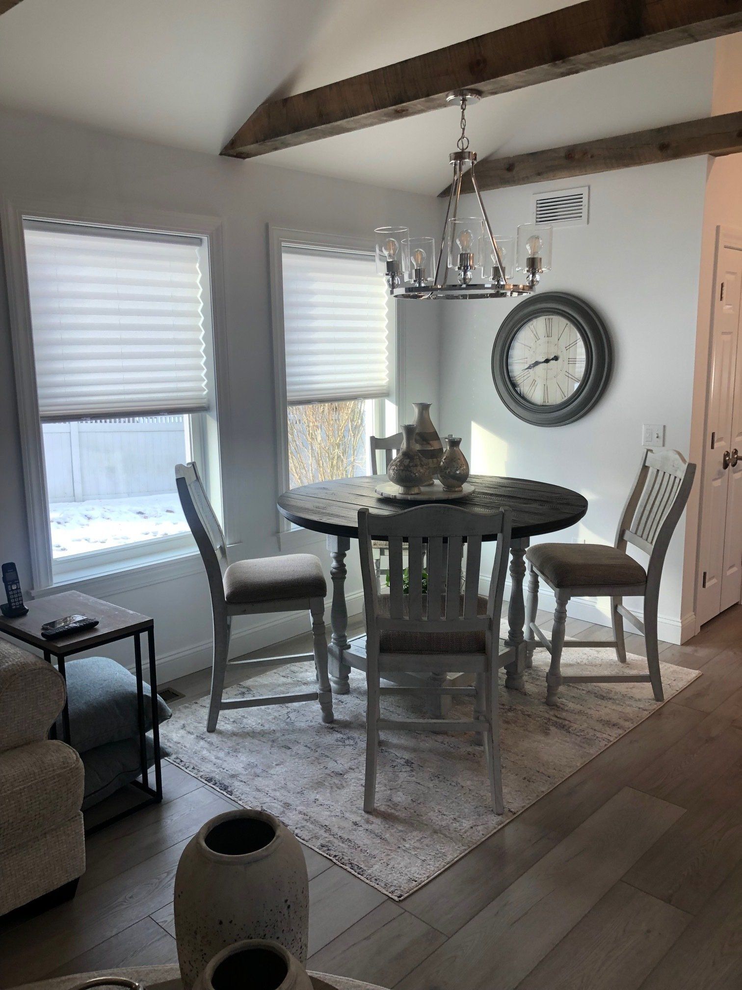 A living room with a table and chairs and a clock on the wall.