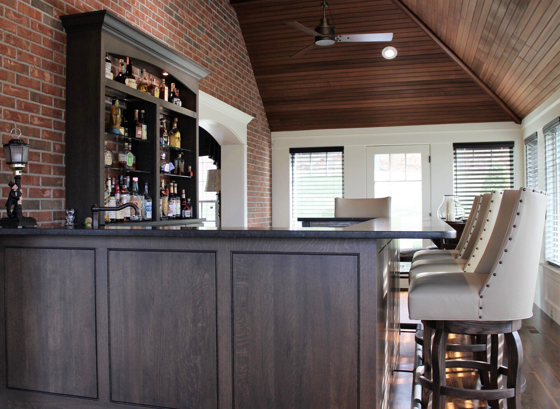A bar in a room with a brick wall and a ceiling fan