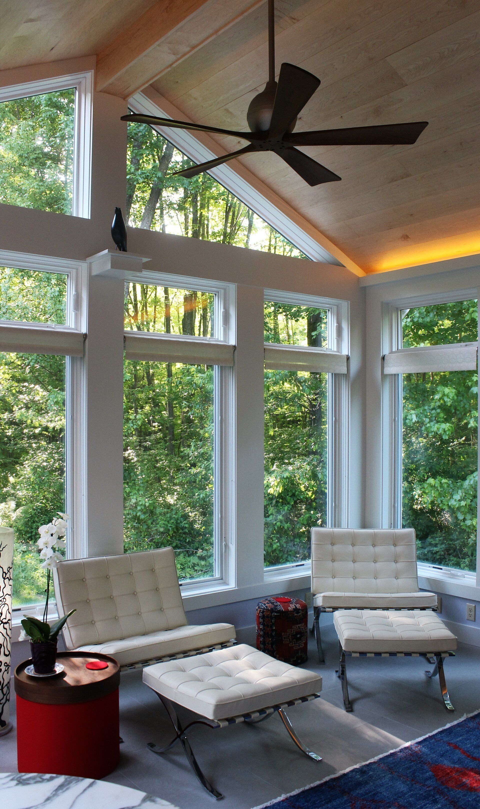 A living room with a lot of windows and a ceiling fan