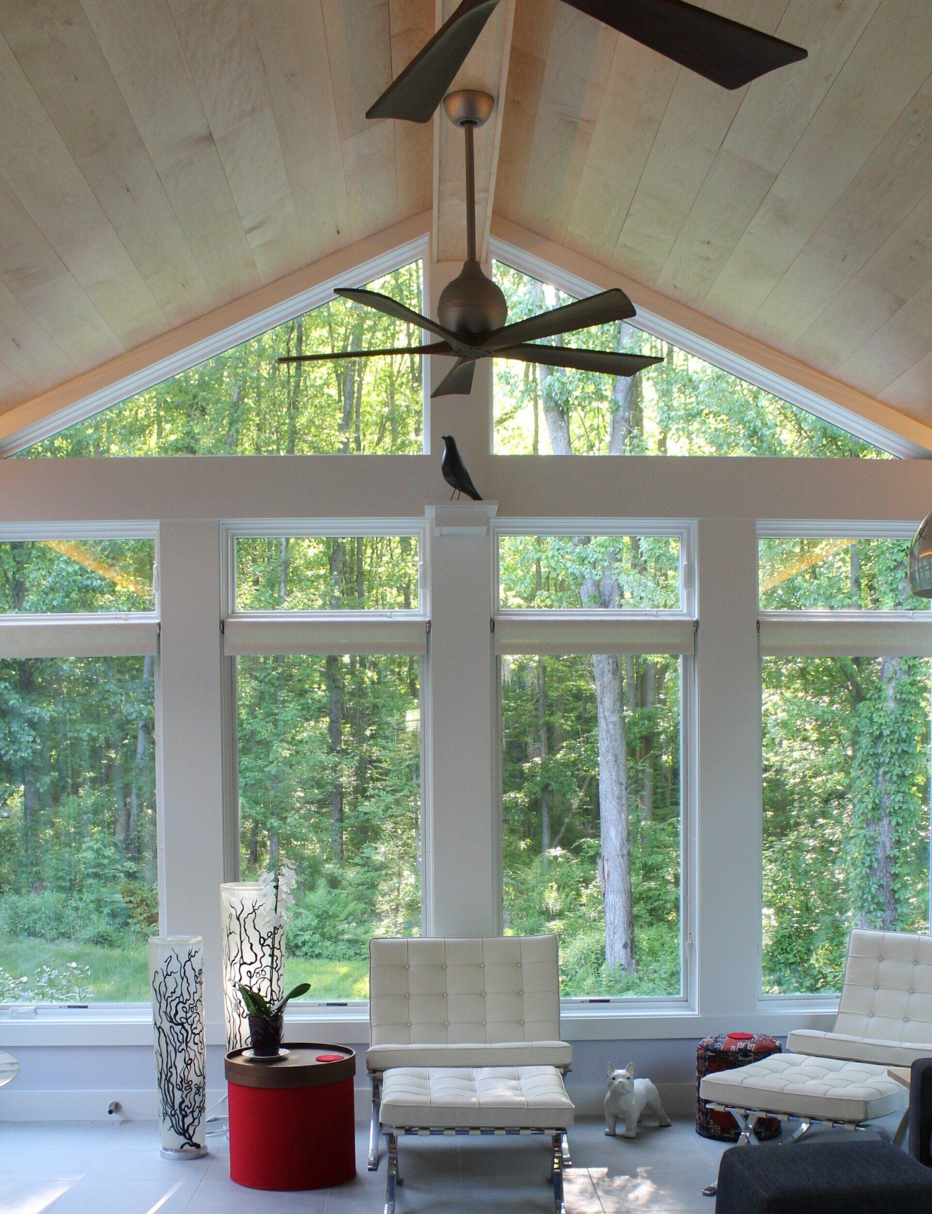A living room with lots of windows and a ceiling fan