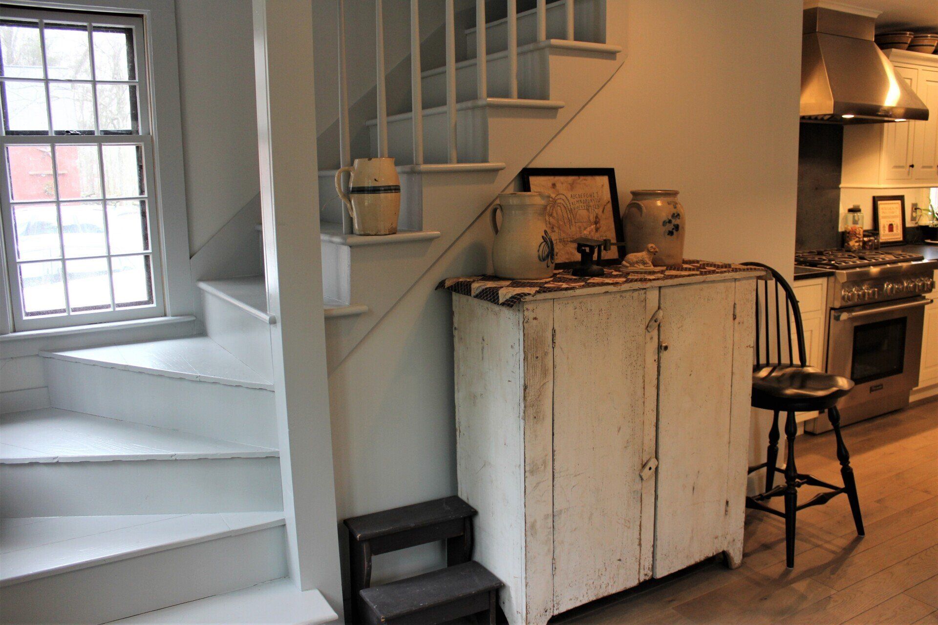 a white cabinet sits under a set of stairs in a kitchen