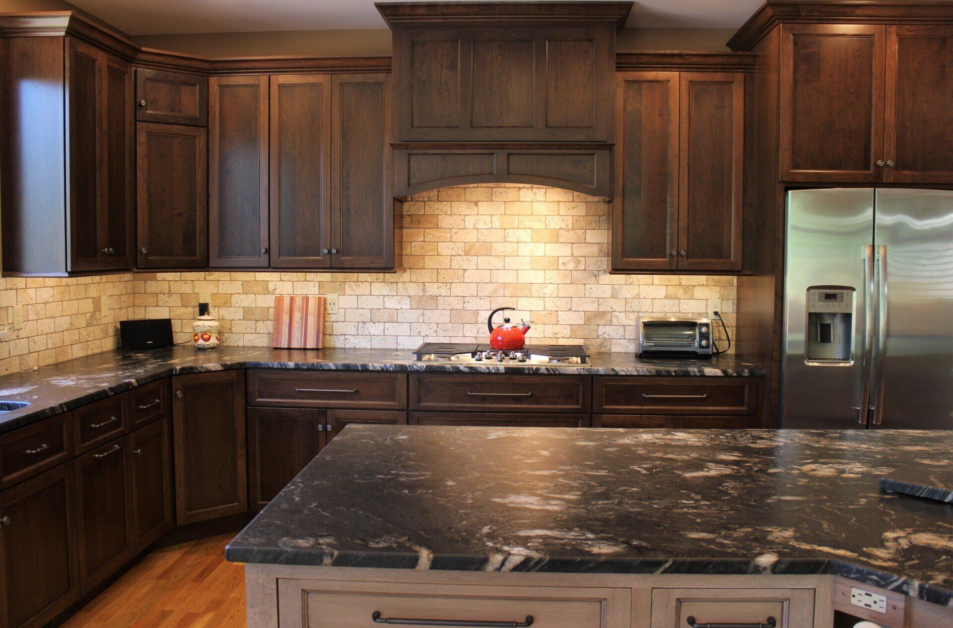 a kitchen with dark cabinets and a stainless steel refrigerator