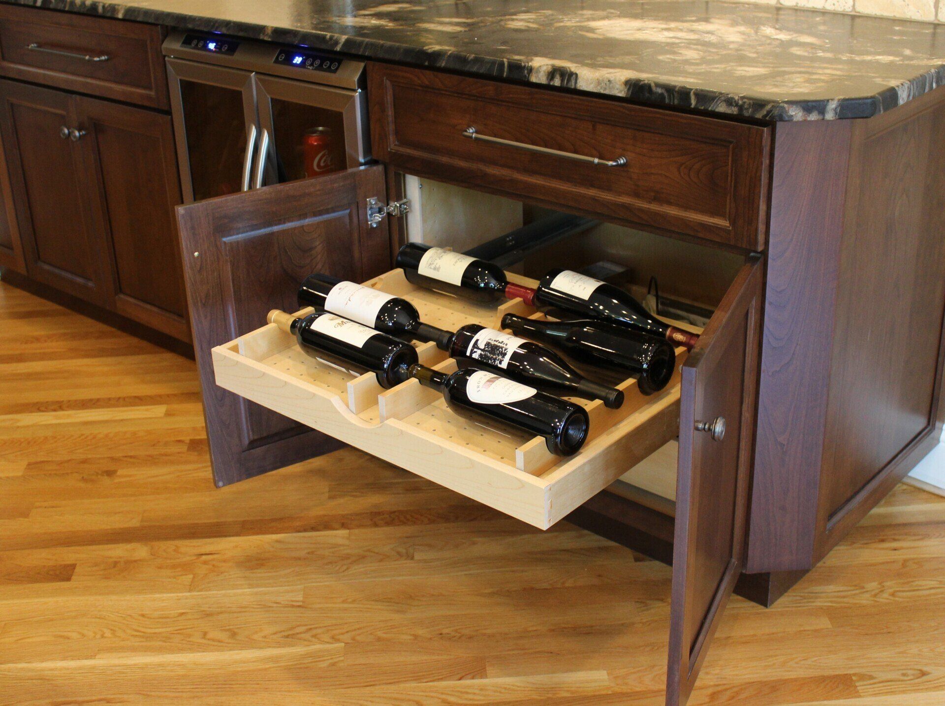 wine bottles are lined up in a wooden tray in a kitchen