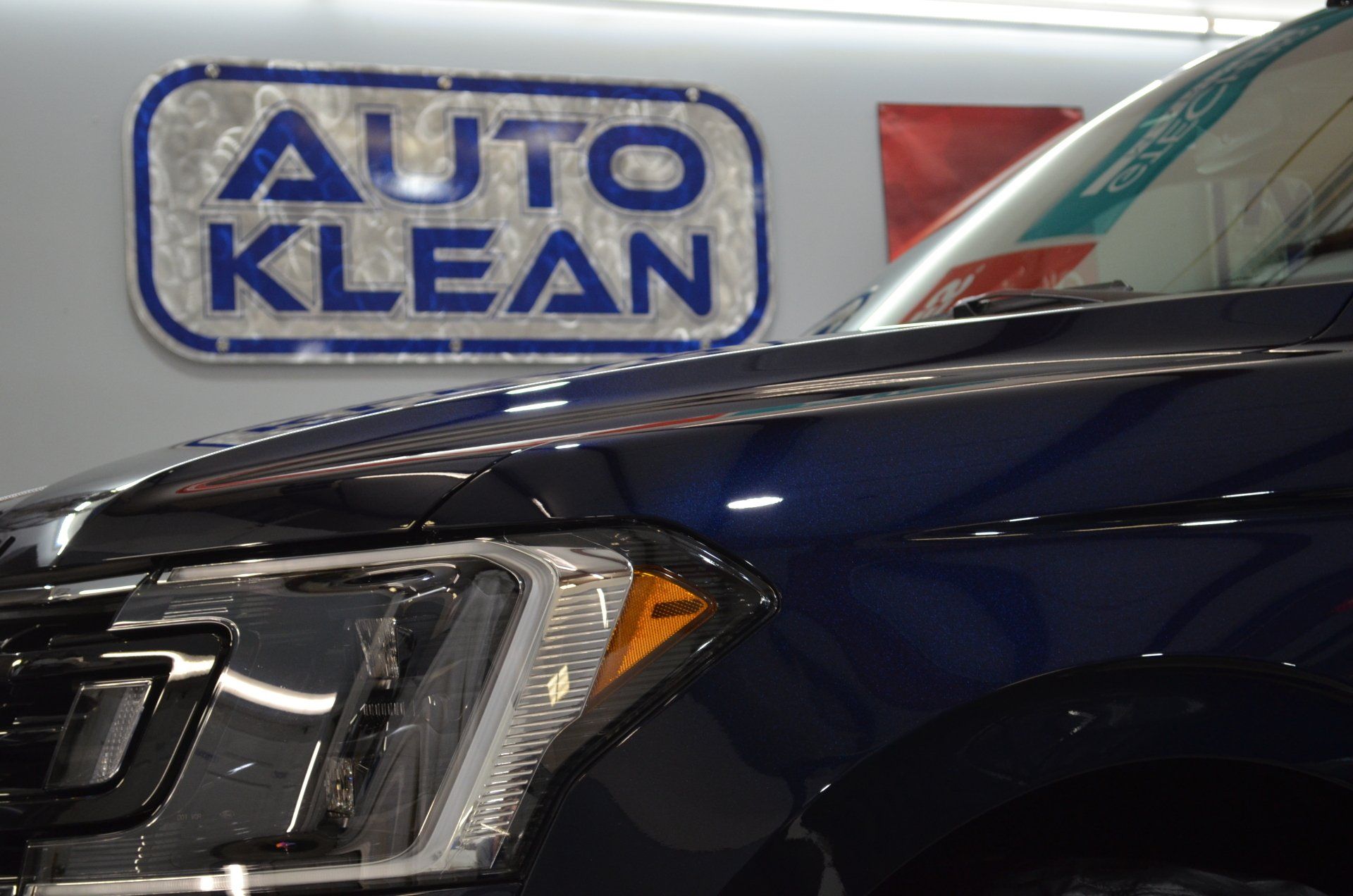 A black car is parked in front of an auto klean sign