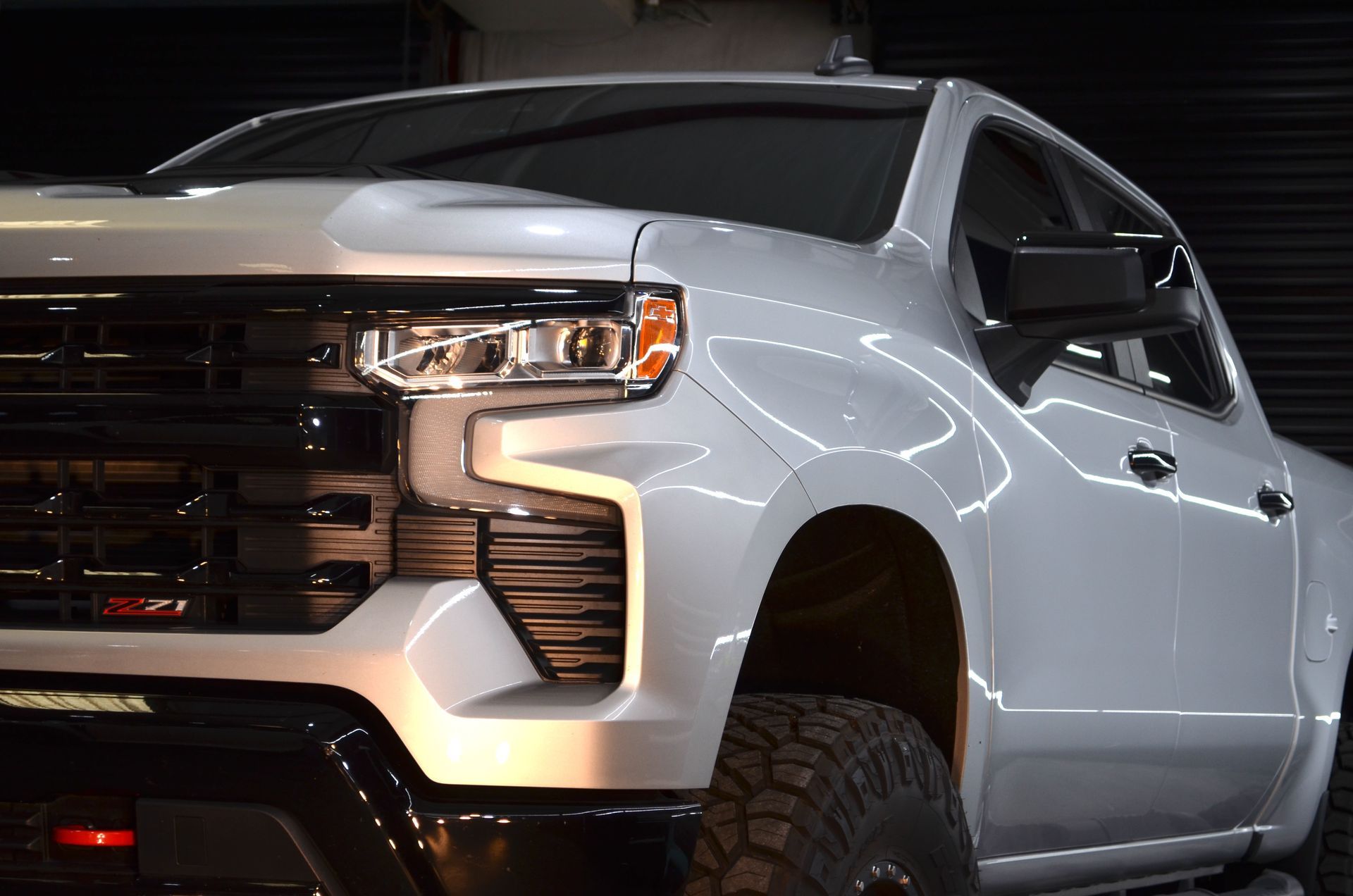 A white truck is parked in a dark garage.