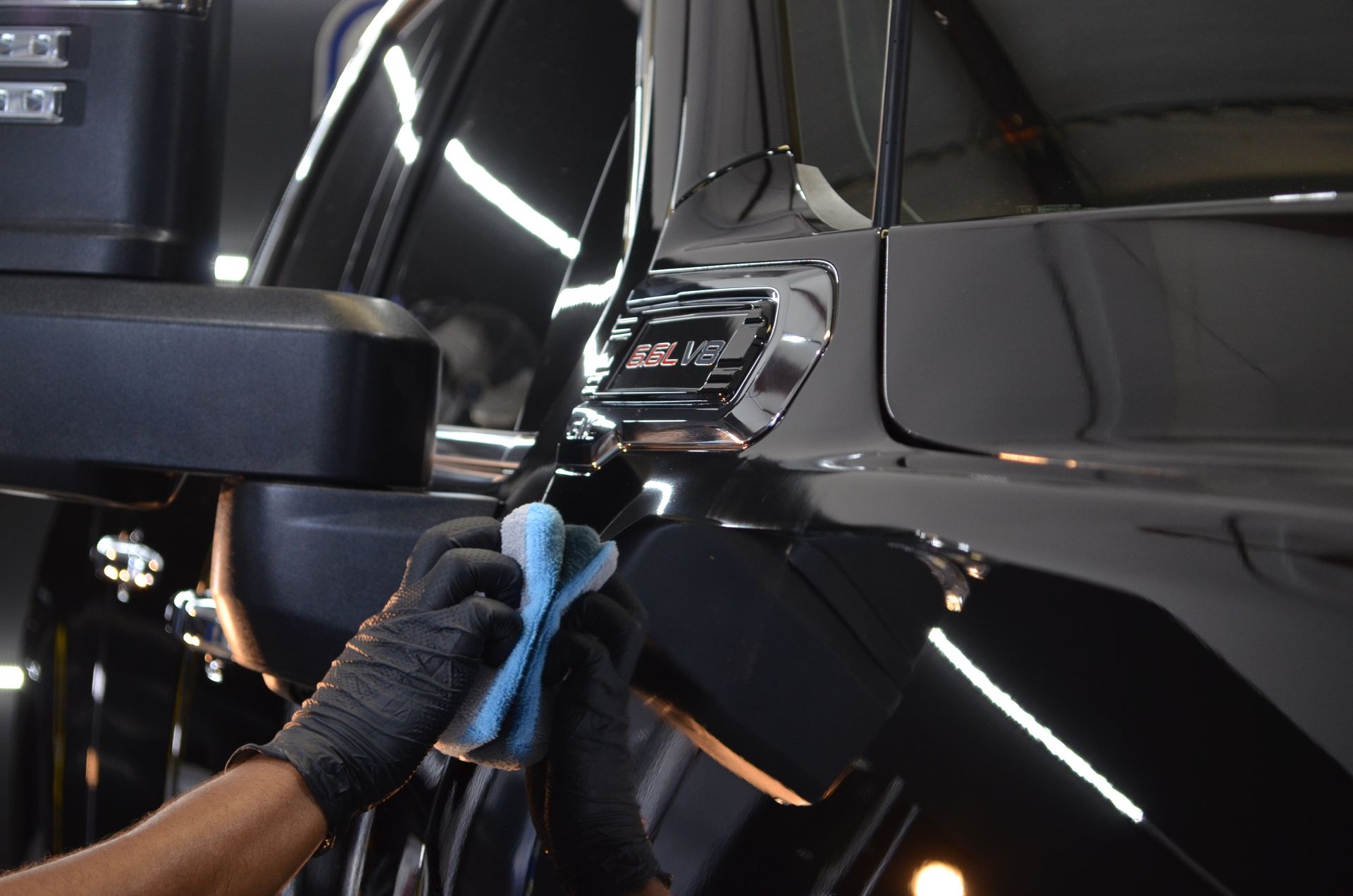 A person is cleaning a black car with a cloth.