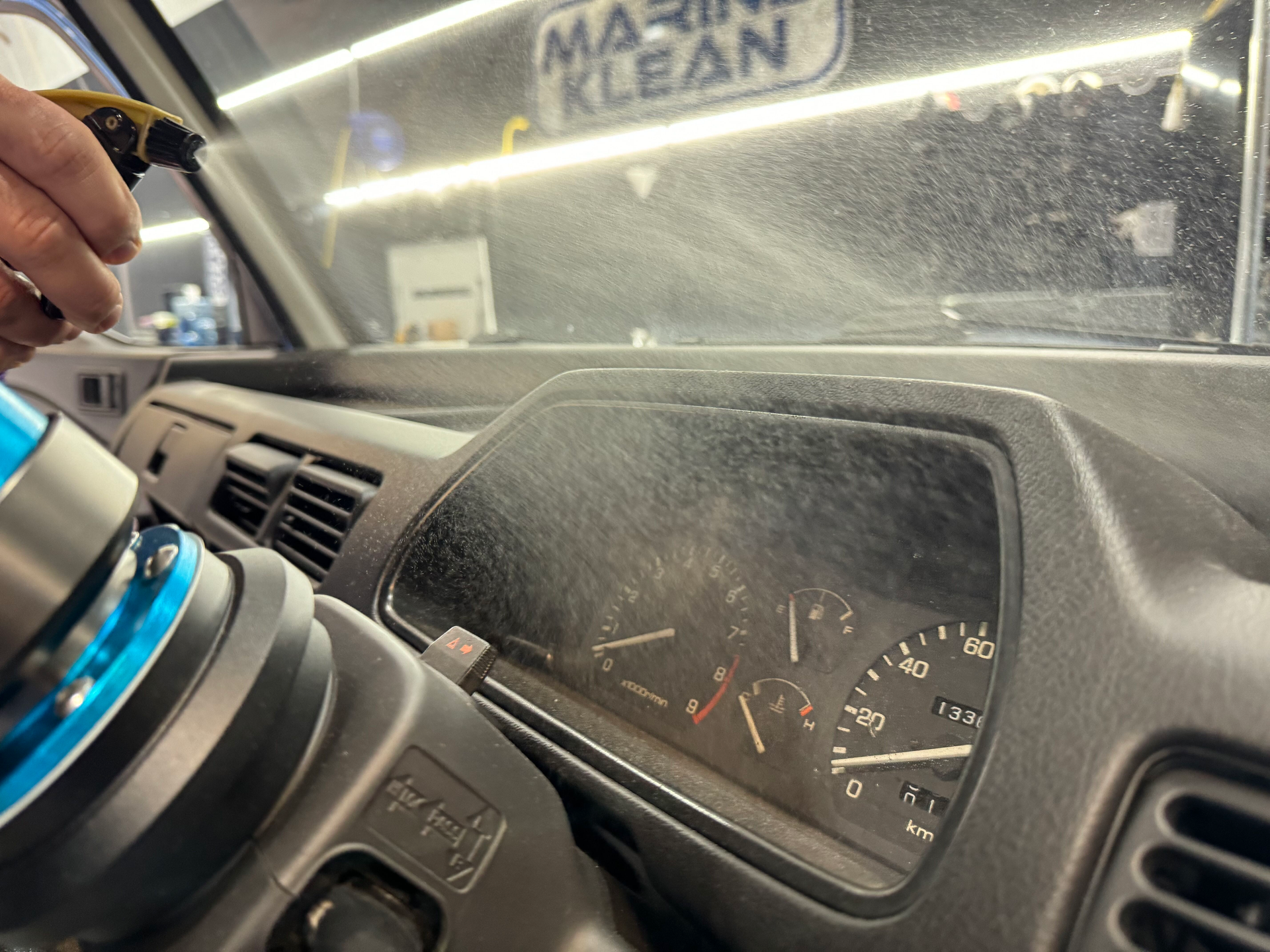 A person is cleaning the dashboard of a car with a spray bottle.