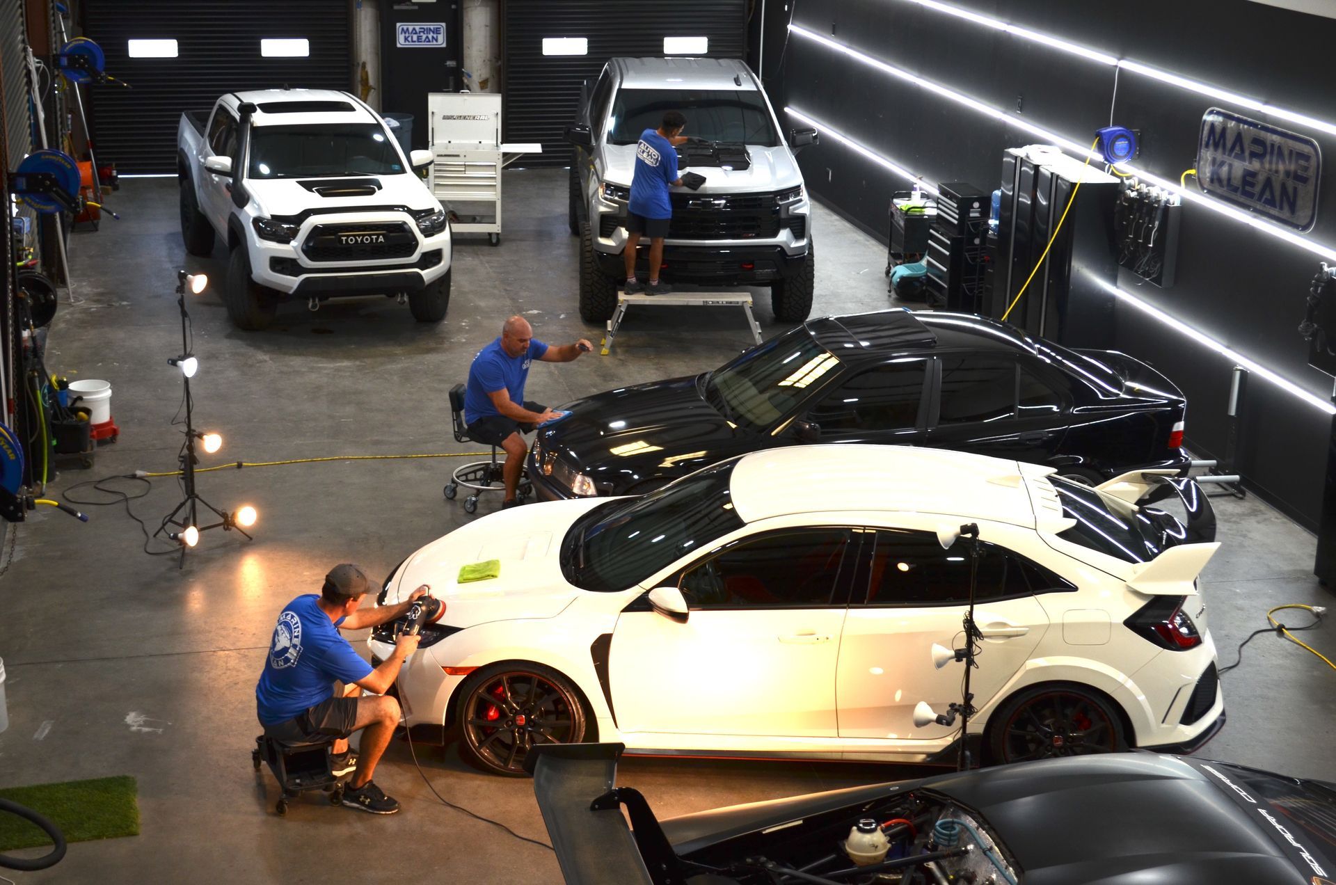 A group of people are working on cars in a garage.