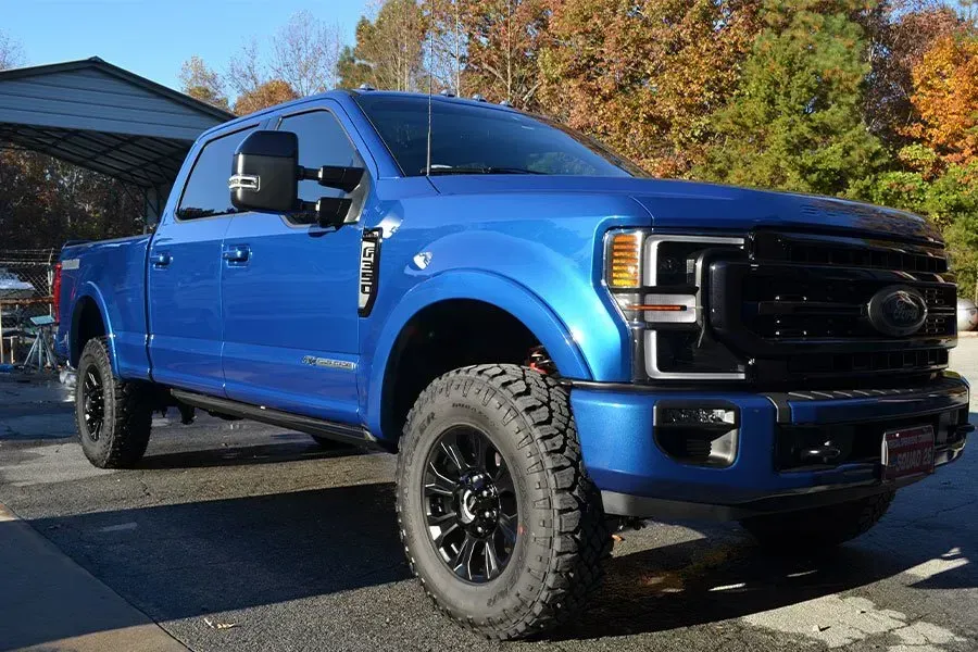 A blue ford truck is parked on the side of the road.