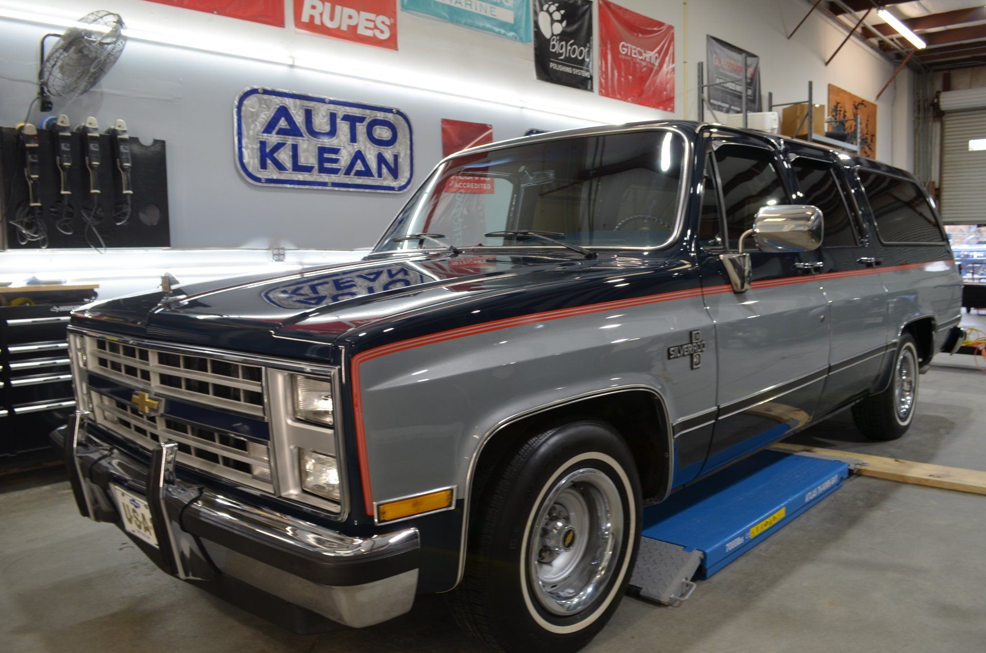 A chevrolet suburban is parked on a lift in a garage.