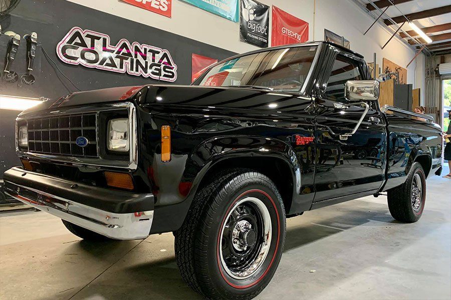 A black truck is parked in a garage next to a sign that says atlanta coatings.