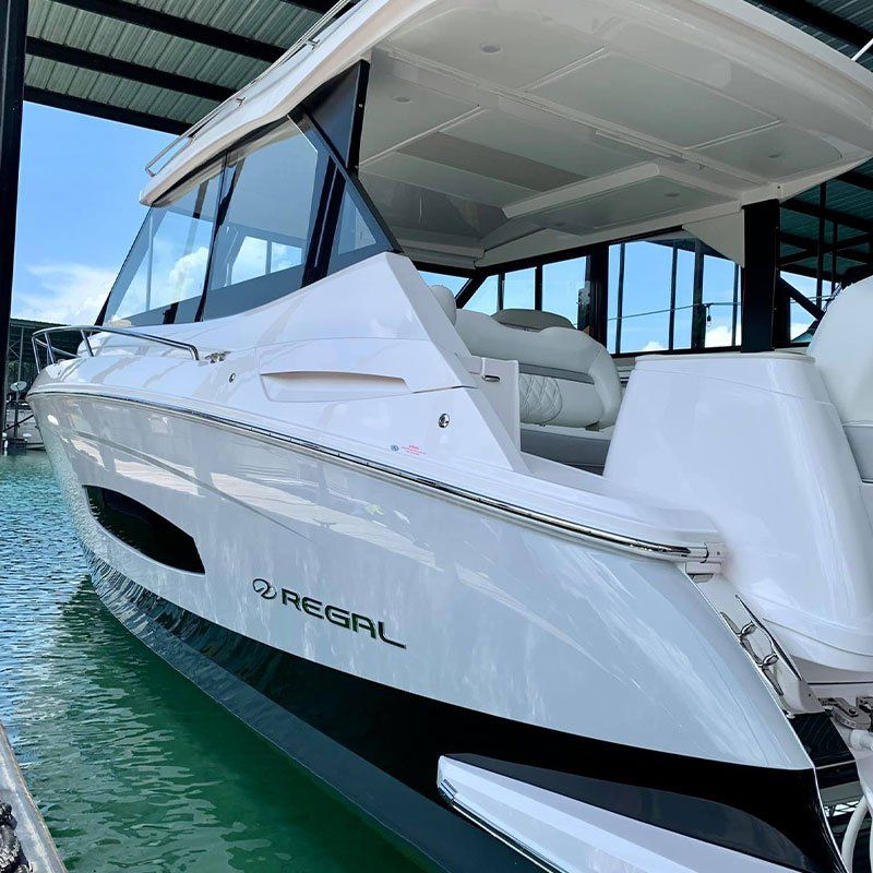 A white regal boat is docked in a marina