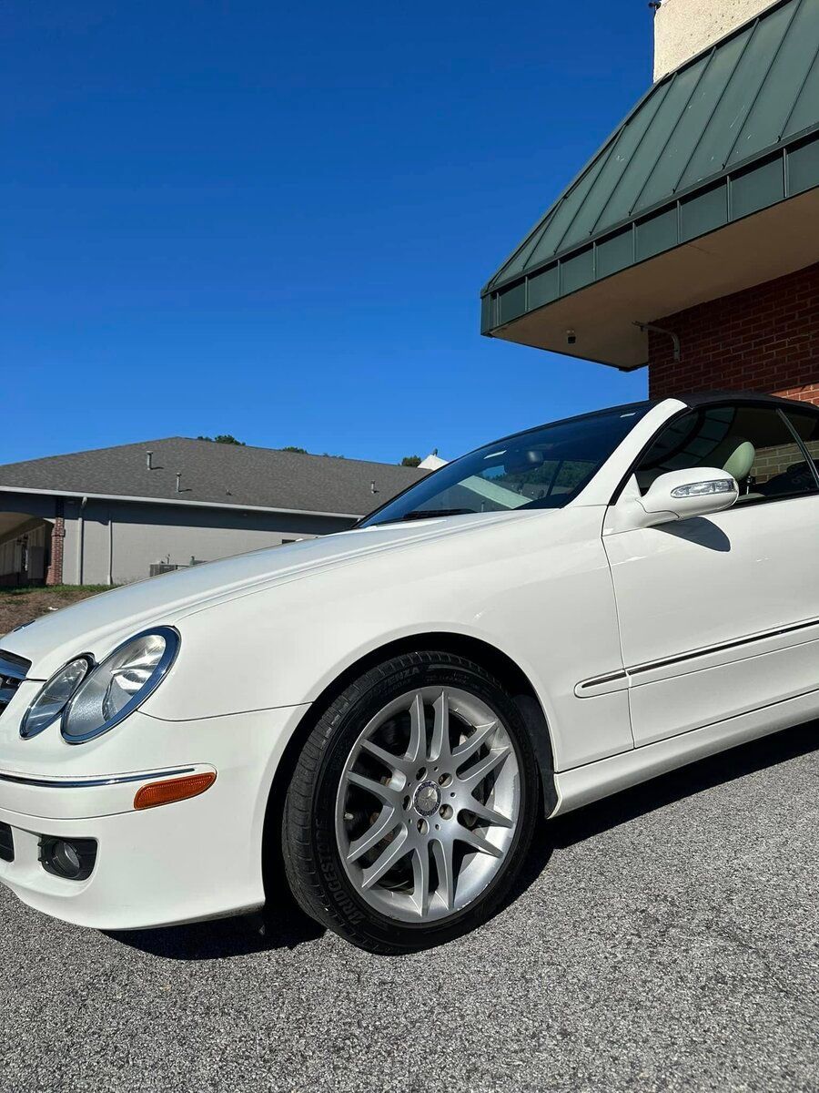 White Mercedes-Benz convertible parked on a sunny day. Building in the background.