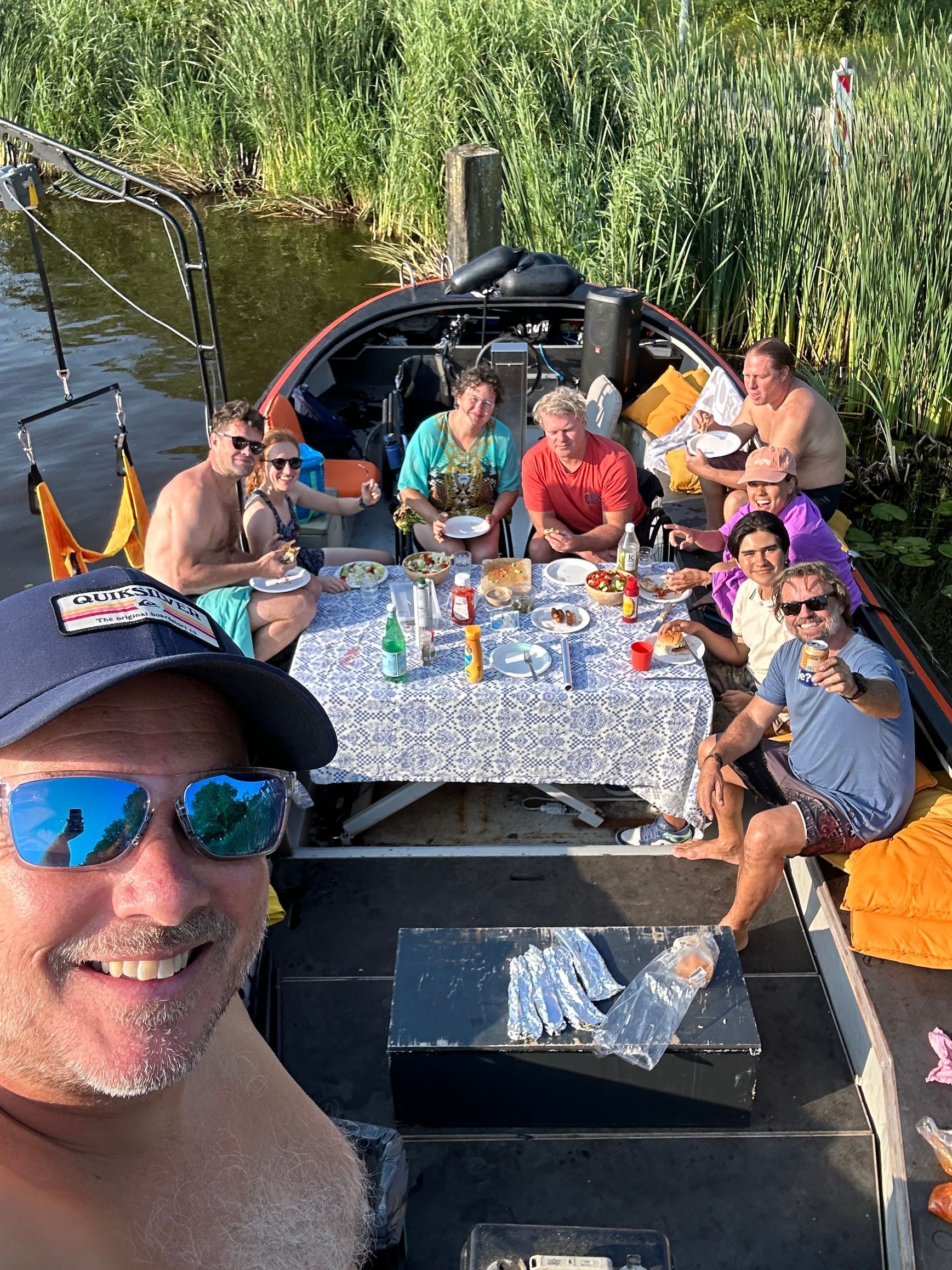 Gezellige rolstoelvriendelijke boottocht in Amsterdam met een BBQ aan boord. Groep mensen geniet van eten op een toegankelijke rondvaart.
