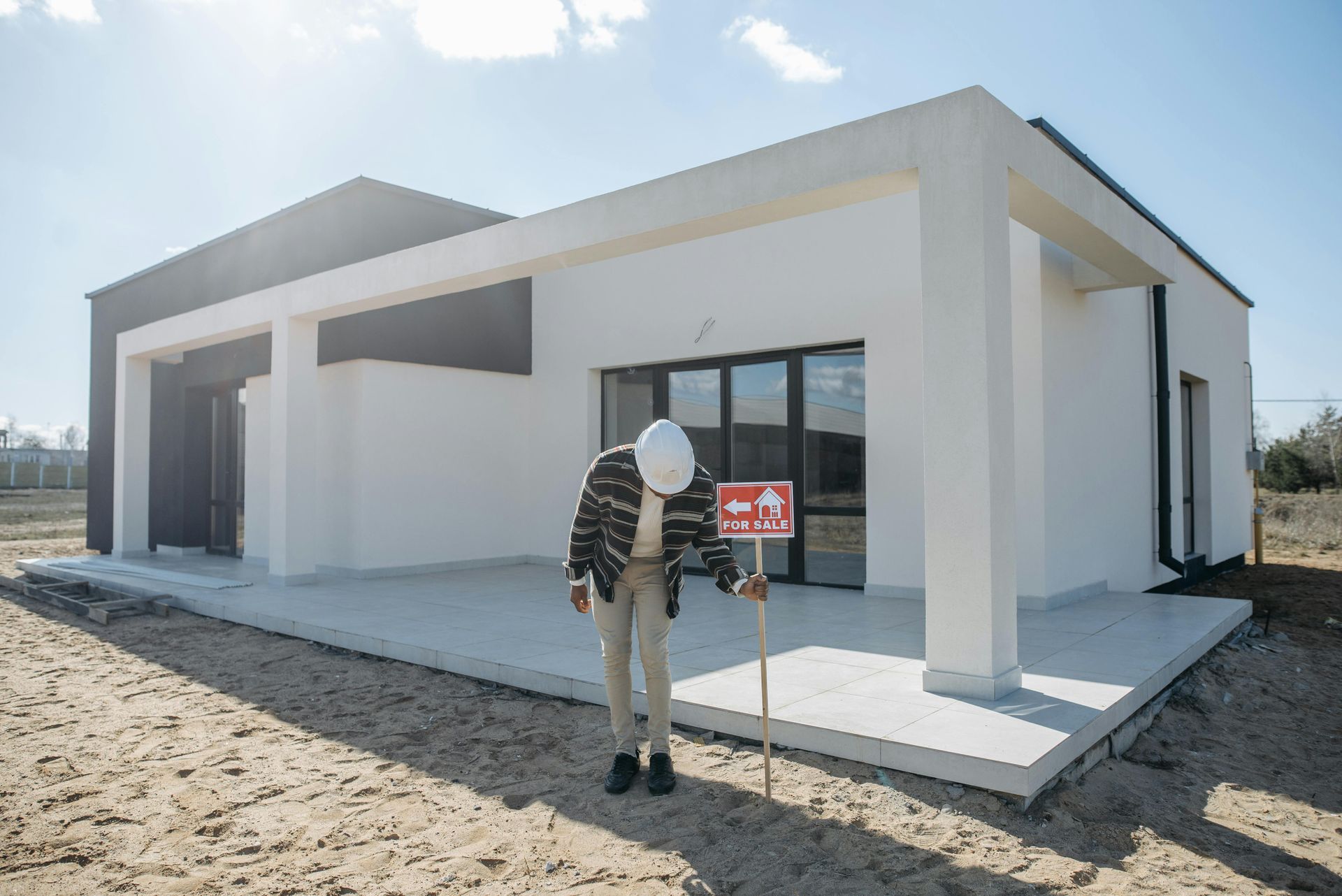 A man in a hard hat is standing in front of a house.