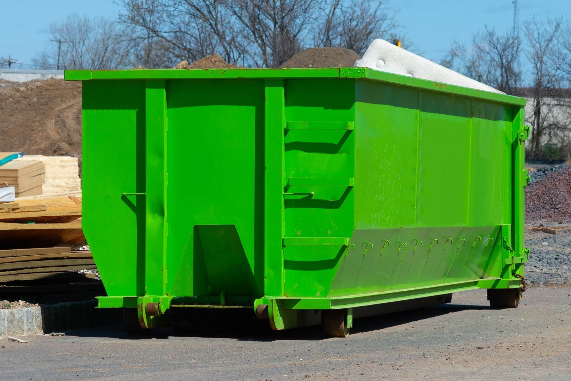 Bright green dumpster on a paved surface, likely for construction debris.