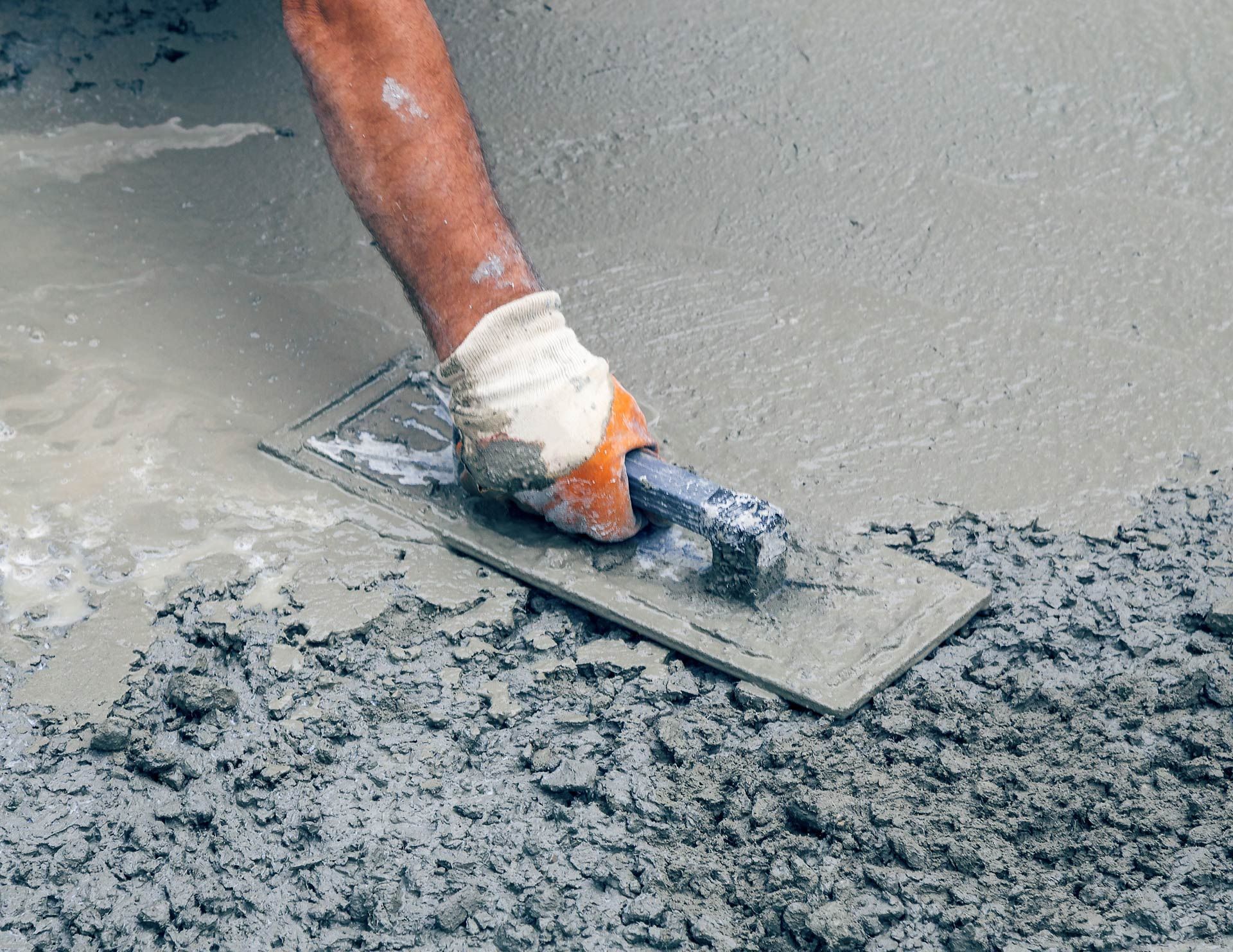 Green dumpster outside a brick building, behind a chain link fence. The top is covered with a light dusting of snow.
