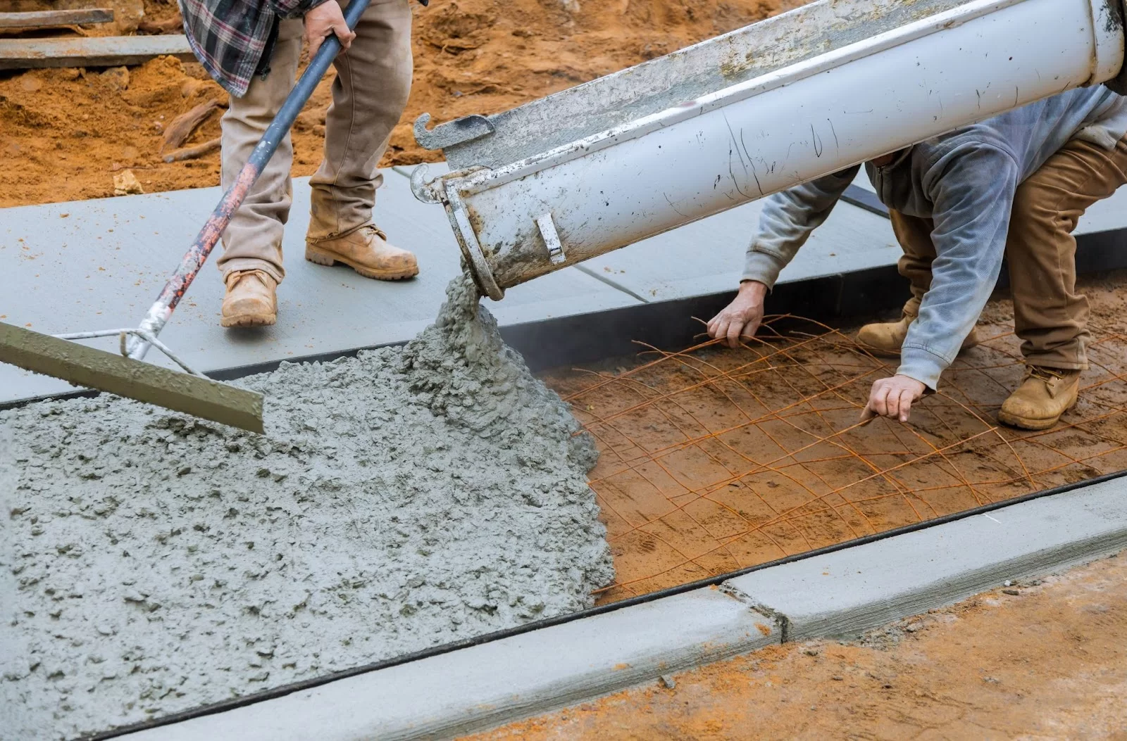 Hand with trowel smoothing wet concrete on a surface.