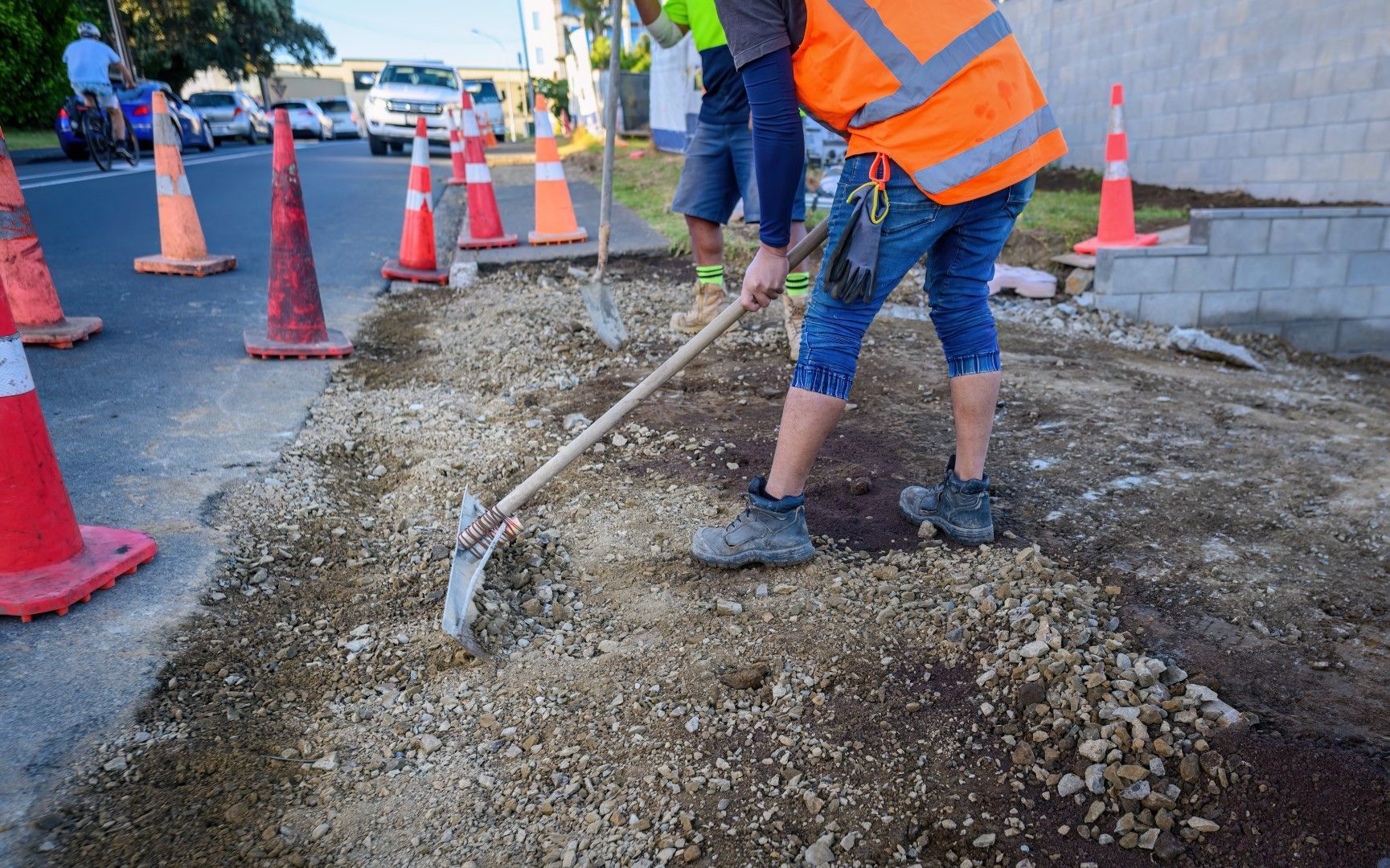 A construction worker is using a shovel to dig a hole in the ground.