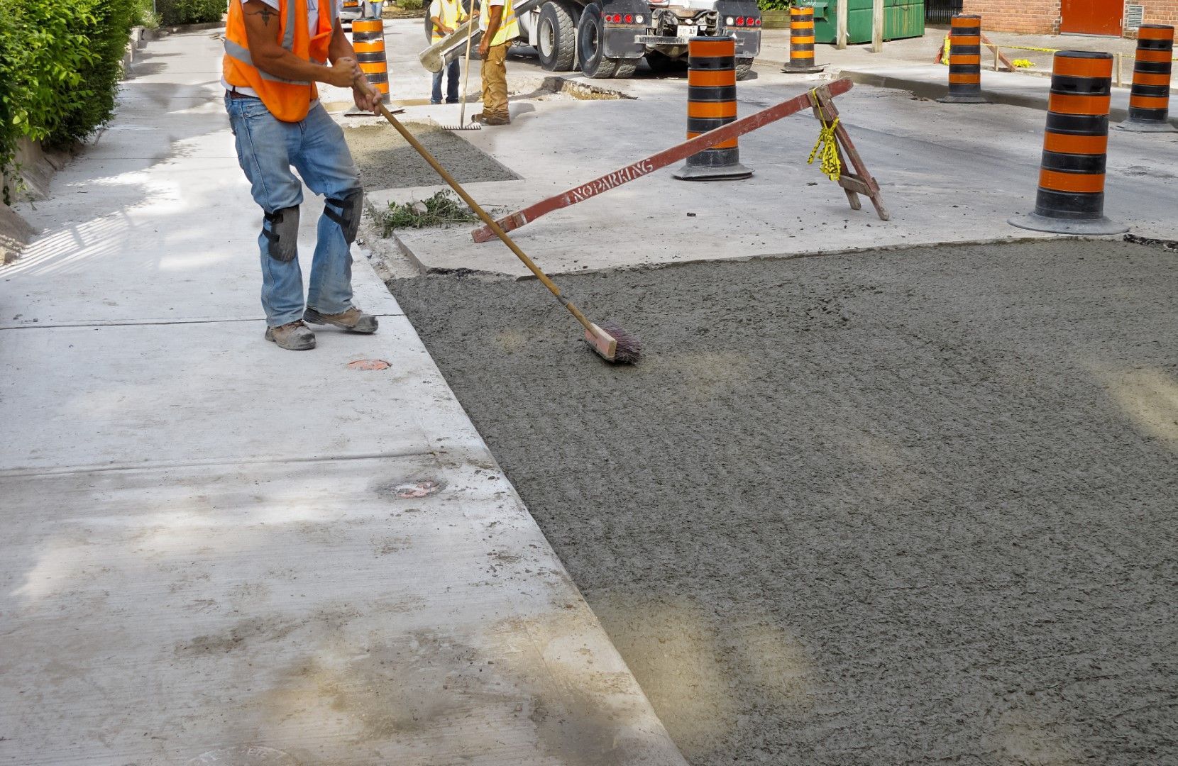 A construction worker is sweeping the ground with a broom