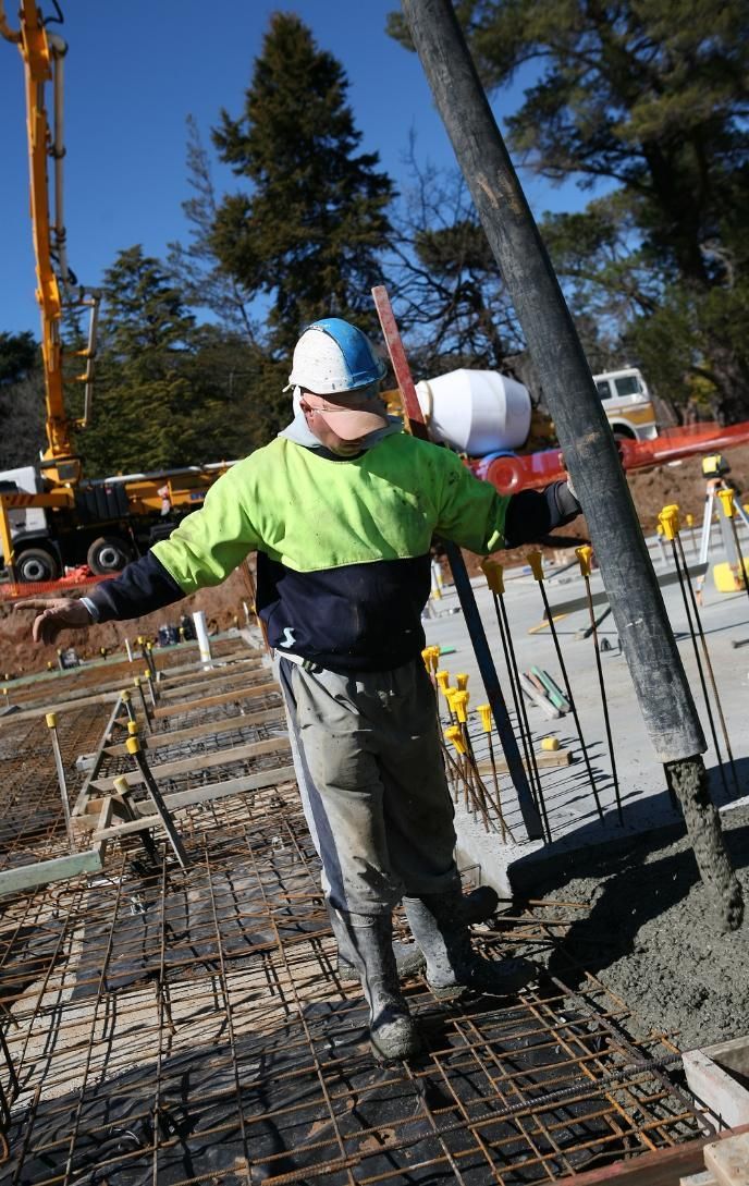 A Man Is Pouring Concrete On A Construction Site — New England & North West Concrete Pumping In Uralla, NSW