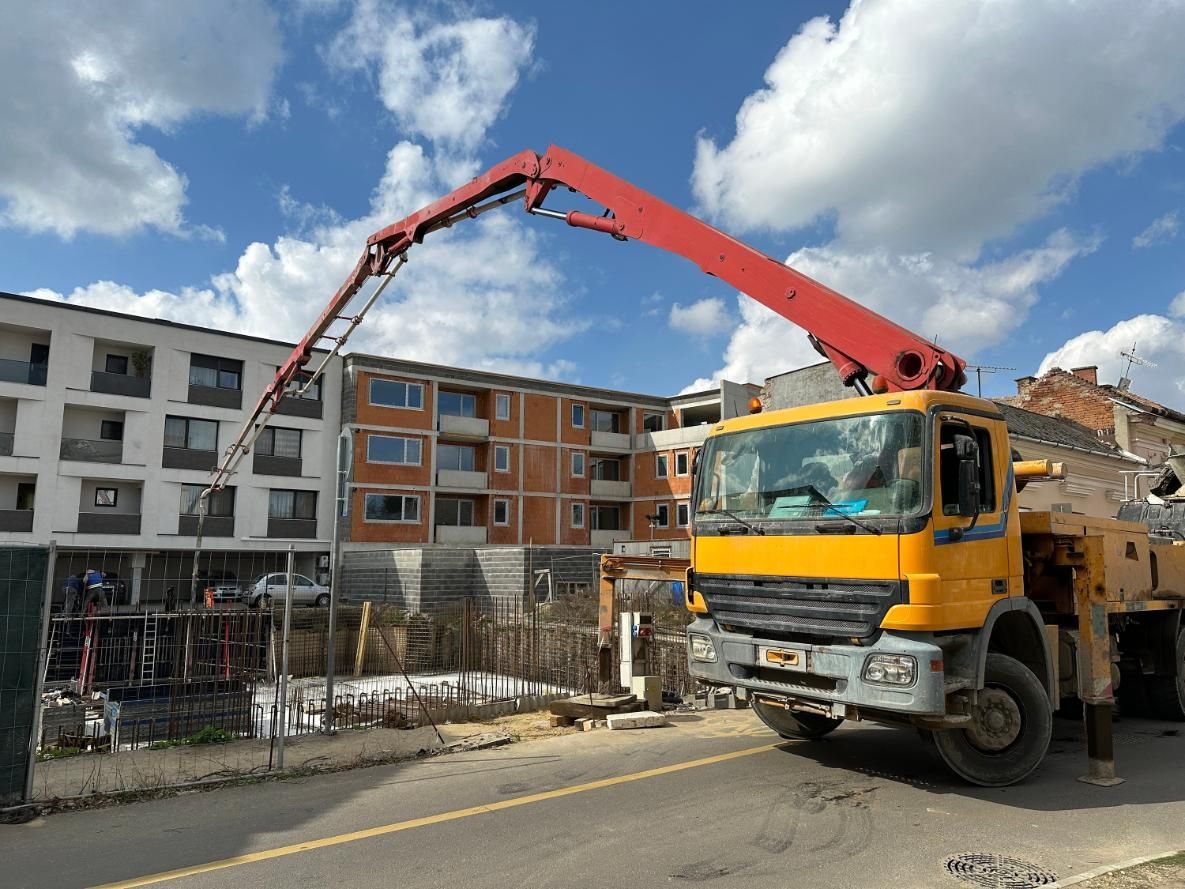 A Yellow And Red Truck With A Crane Attached — New England & North West Concrete Pumping In Uralla, NSW