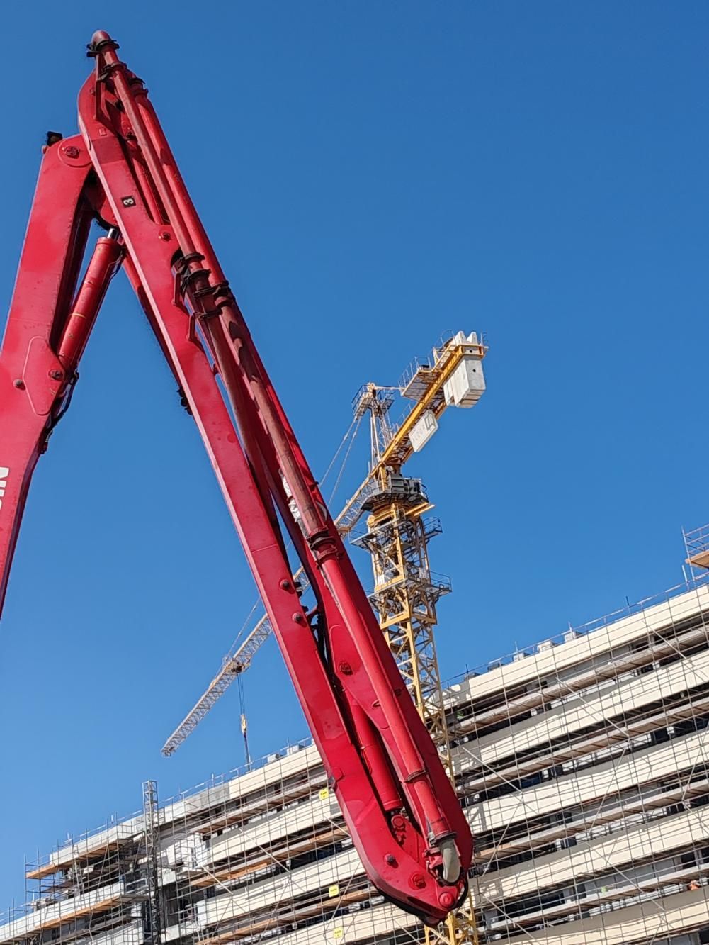 A Red Concrete Pump Is Sitting In Front Of A Building — New England & North West Concrete Pumping In Uralla, NSW