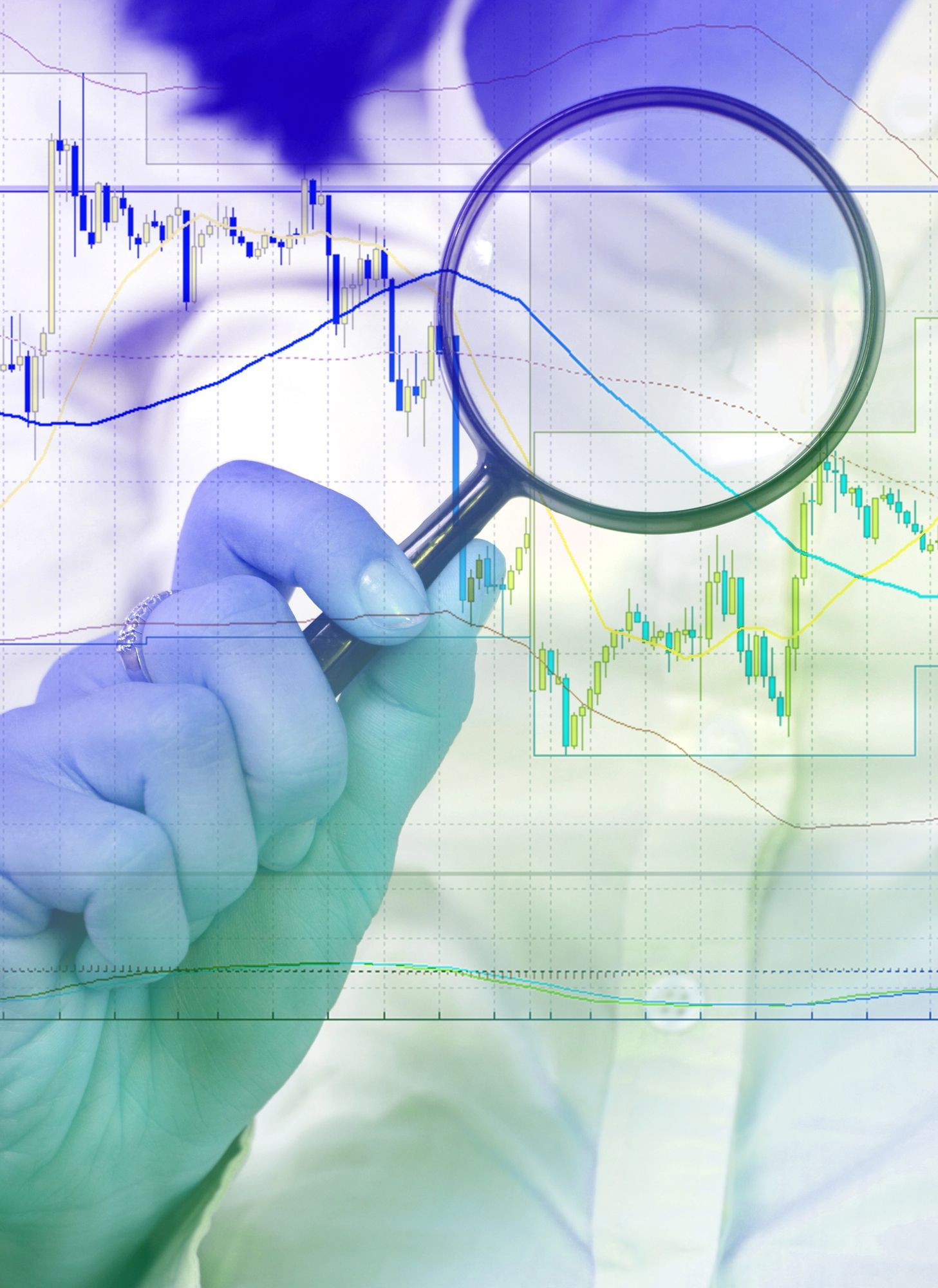 Hand holding magnifying glass over stock market graph.