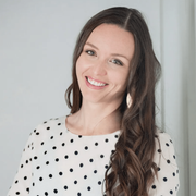 A woman wearing a white polka dot dress is smiling for the camera.