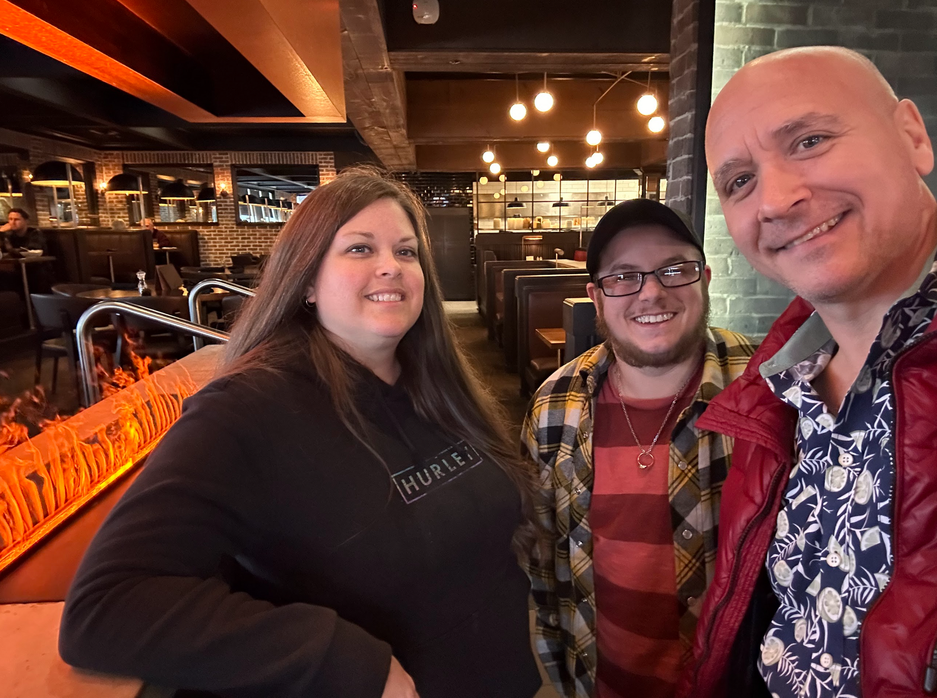 Three people are posing for a picture in a restaurant.