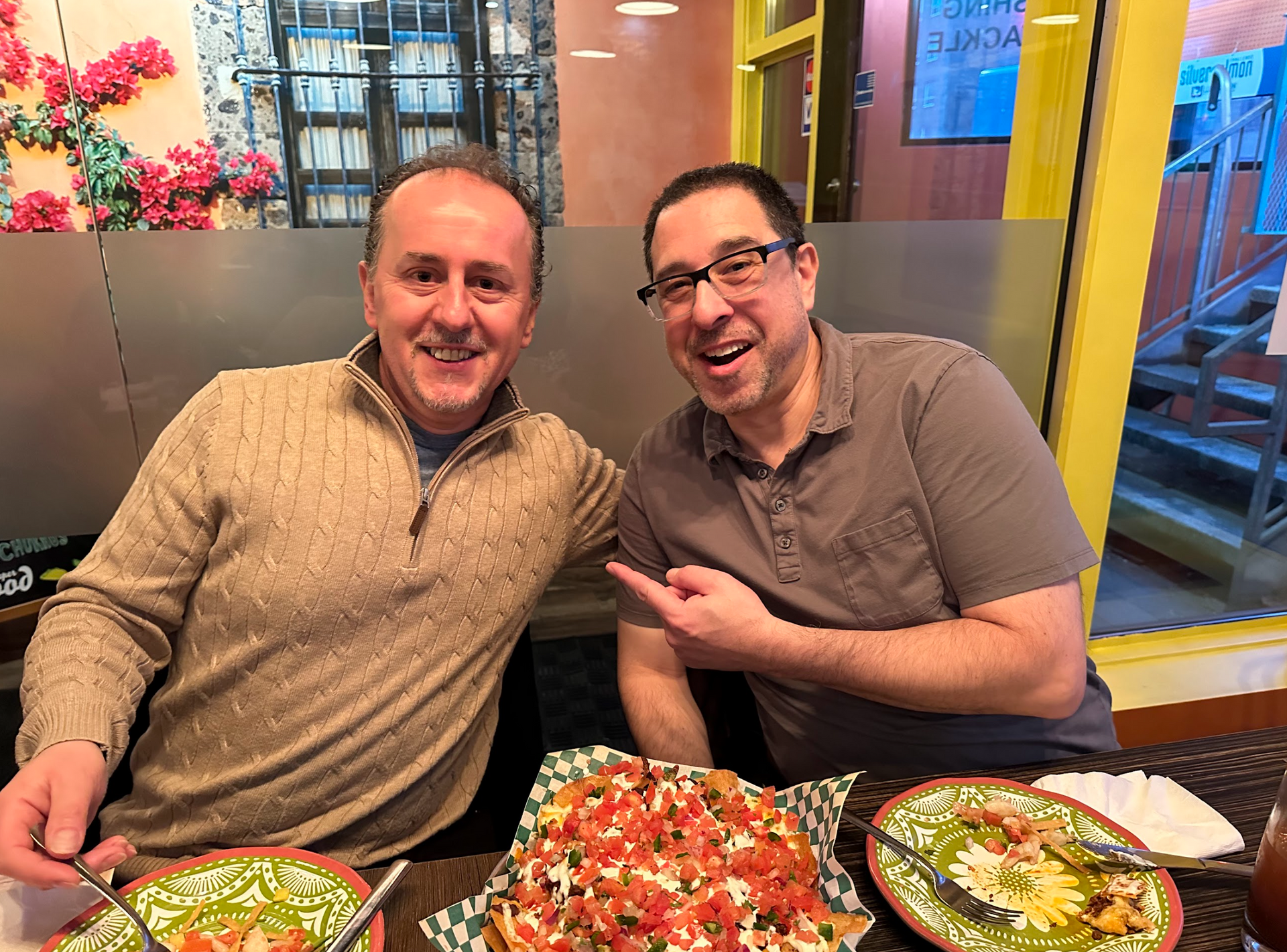 Two men are sitting at a table with plates of food.